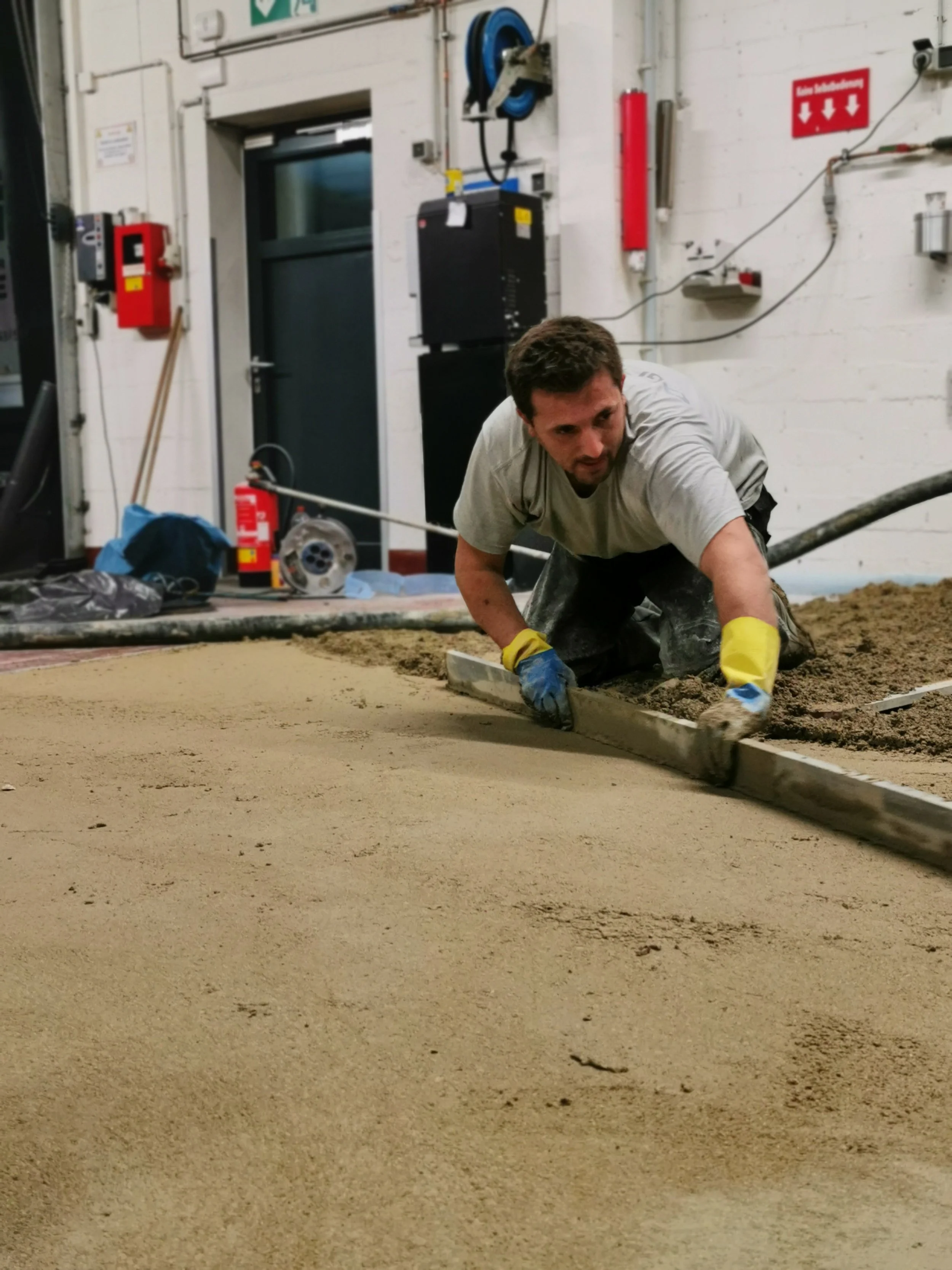 Estricharbeiten Edis in Aktion  mit Geräten und abziehlatte