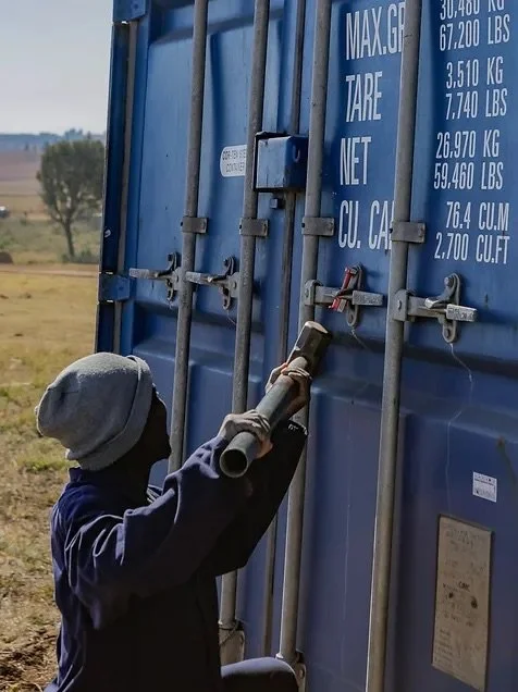 Person opening a blue shipping container shipped to Challenge Ministries in eSwatini