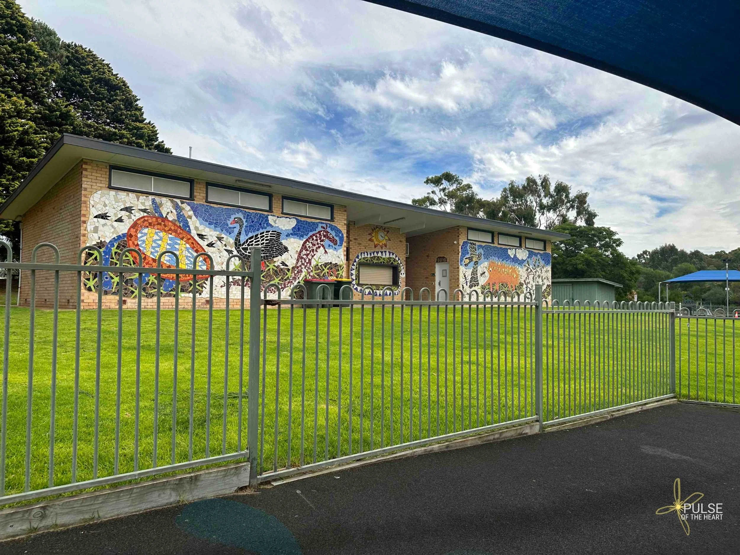 Naracoorte Swimming Lake shaded area, fence and public toilet block with mosaic mural.