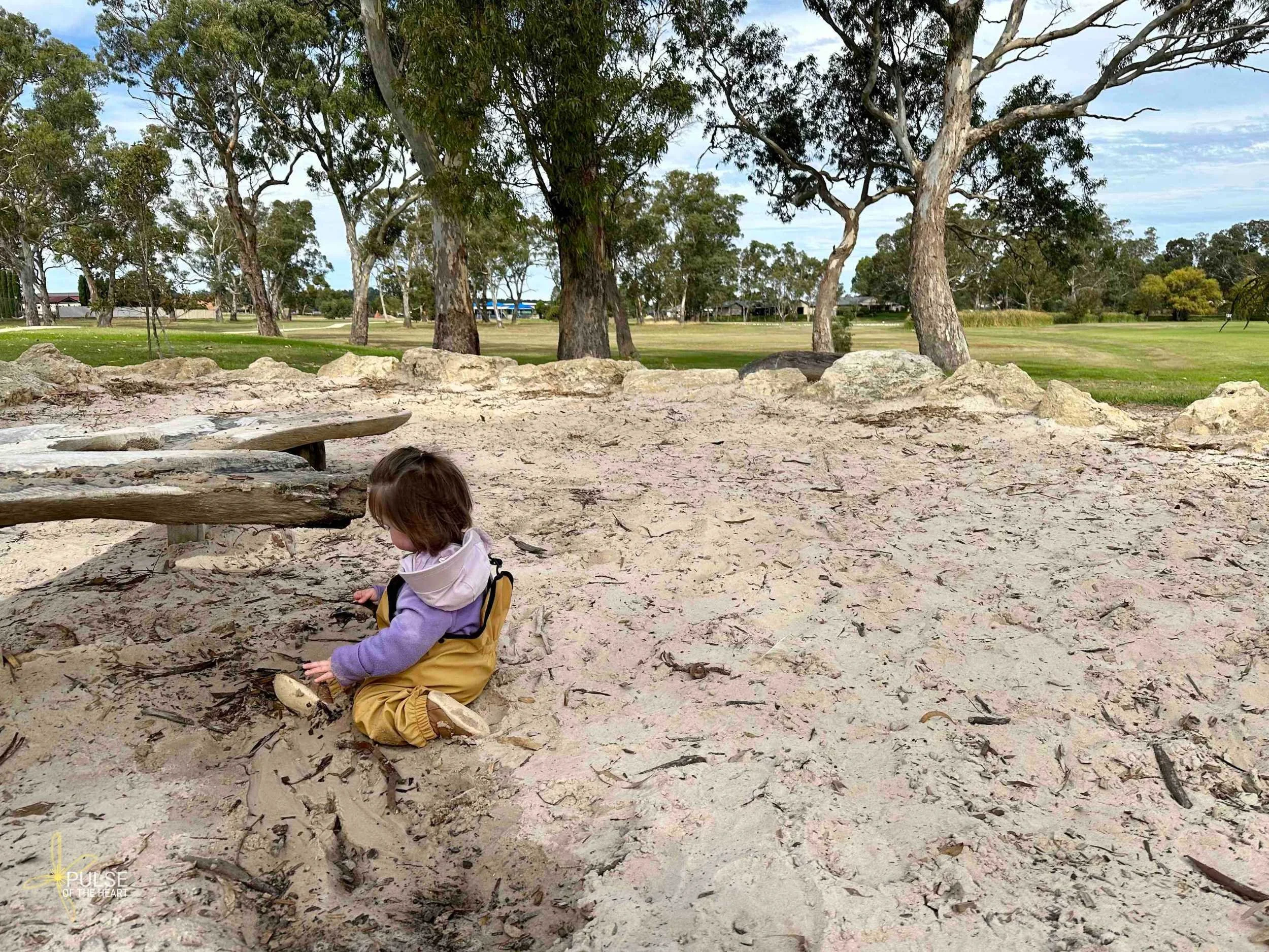 Toddler plays in wet sand at Memorial Oval nature play space.