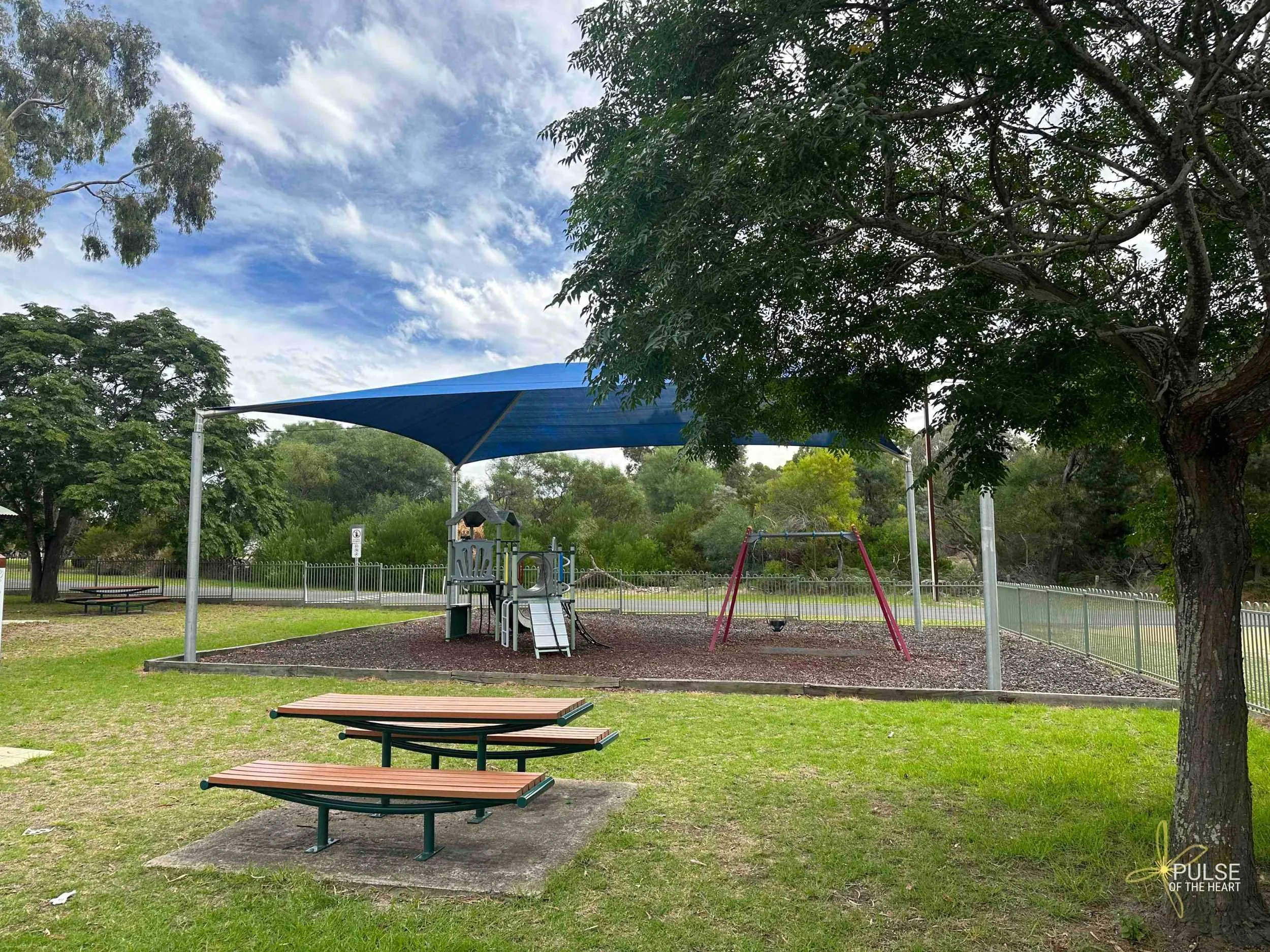 Small shaded playground at Naracoorte Swimming Lake next to unshaded picnic table.