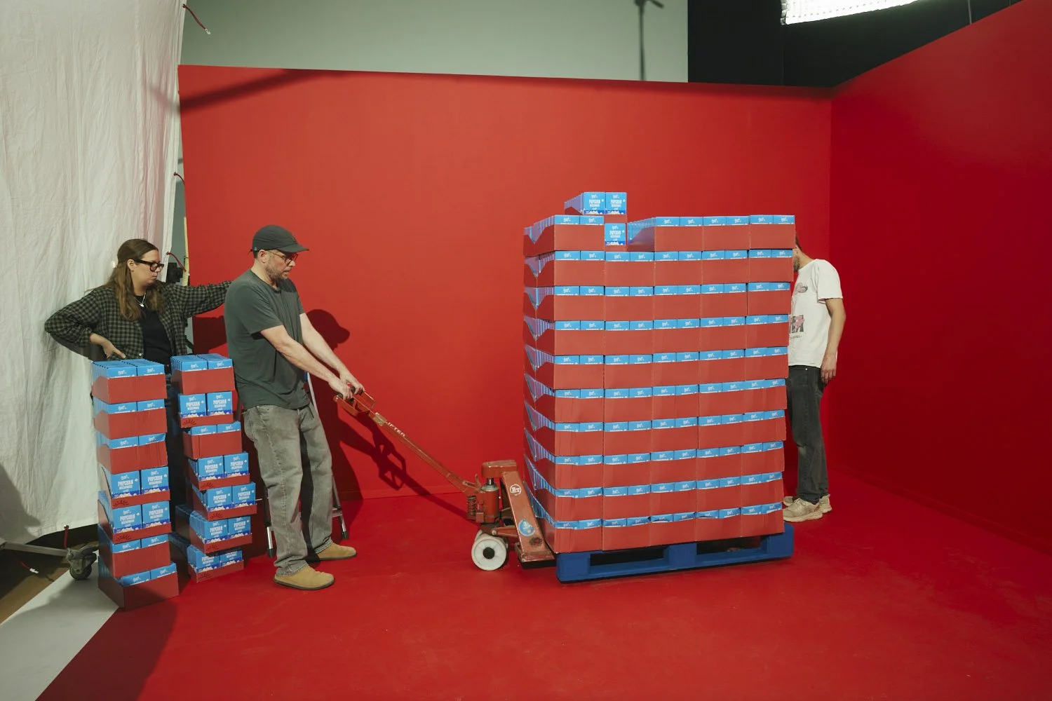People stacking and moving boxes of Kraft Macaroni & Cheese in a red studio with a red floor and wall.