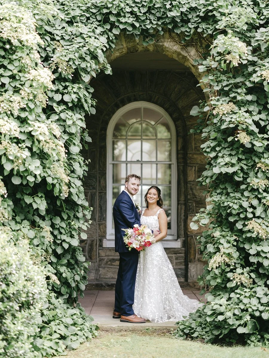 Bride and groom in an archway of greenery at the Ivy at Ellis Preserve in Newtown Square, PA