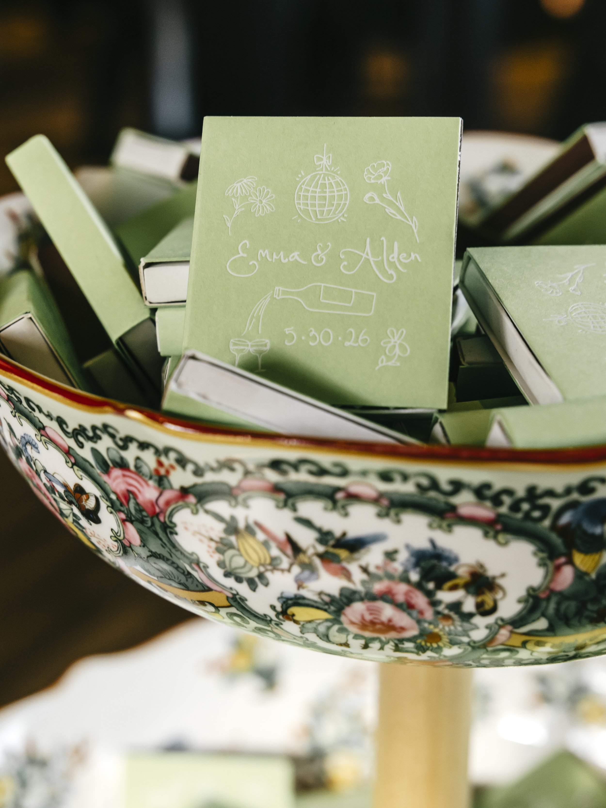 custom illustrated matchbox with white foil print on green background, displayed in a gorgeous bowl stand.