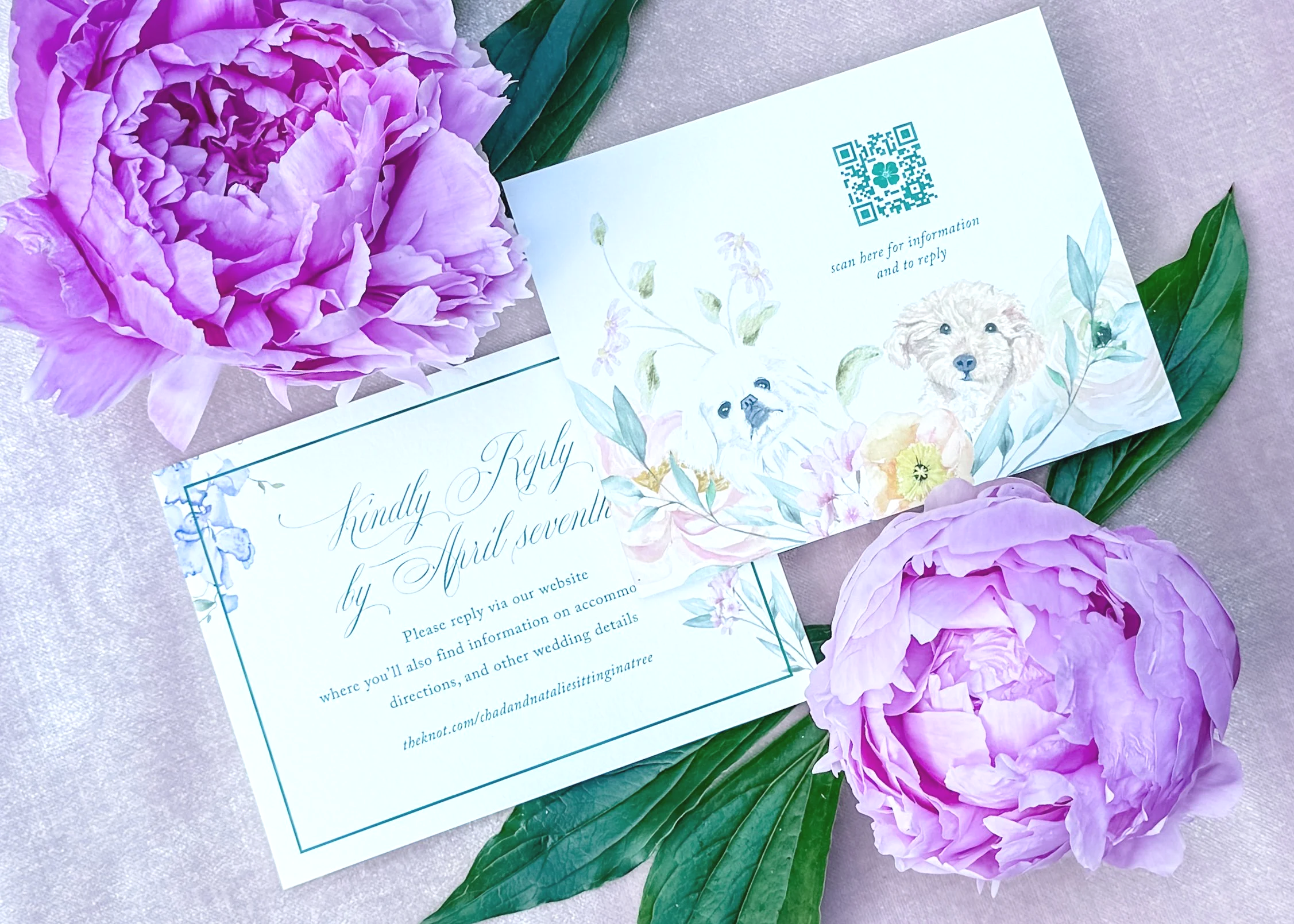 Wedding response card with a QR code placed discreetly on the back of the card amid watercolor flowers and the couple’s pups. Surrounded by pink peonies on a pink velvet surface.