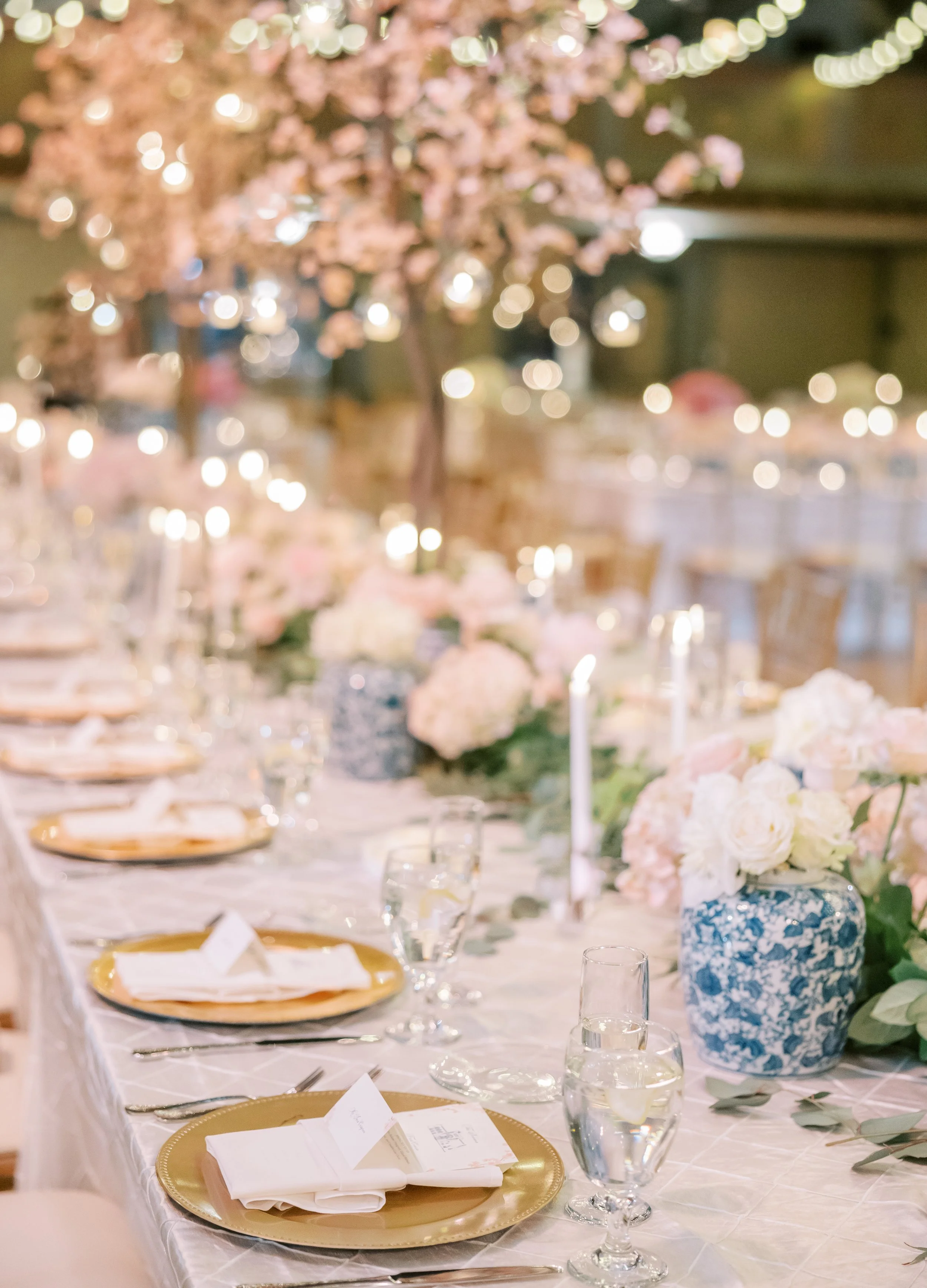 A beautiful tablescape from an April wedding with gold chargers, cherry blossoms, and ginger jars.