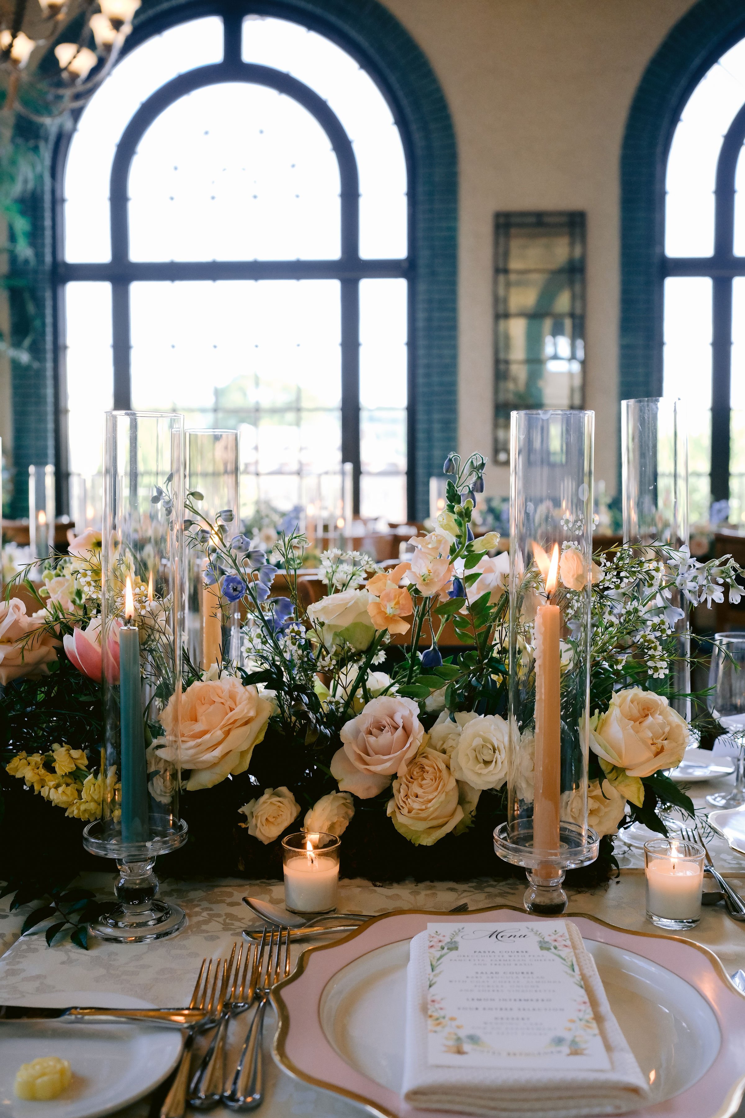 A beautiful place setting with menu in a setting of gorgeous flowers, candles and huge arch windows at the Hotel Bethlehem.