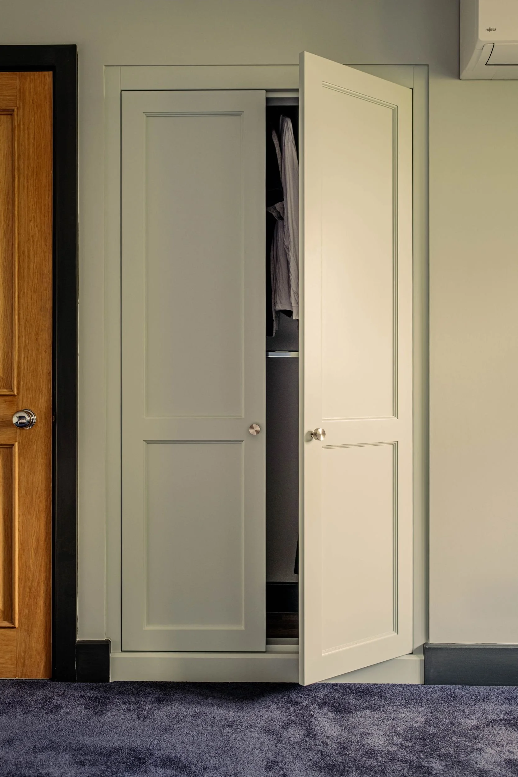 A painted made to measure wardrobe with Shaker style doors with beaded panels. The right hand door is slightly open.