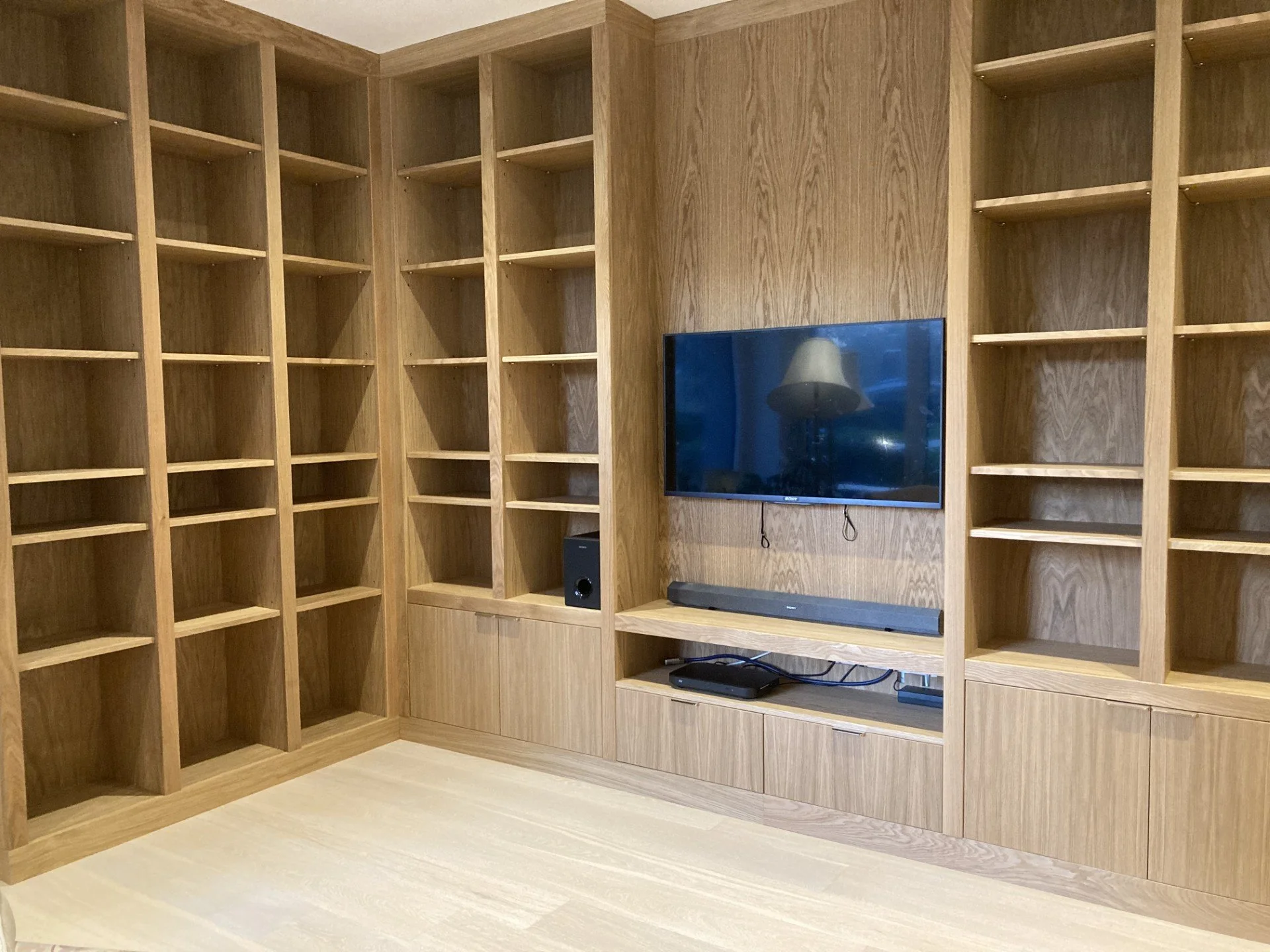 Large made to measure bespoke media unit made from oak veneer and solid oak. media unit consists of a base unit cupboard section and a top unit section with adjustable shelving.