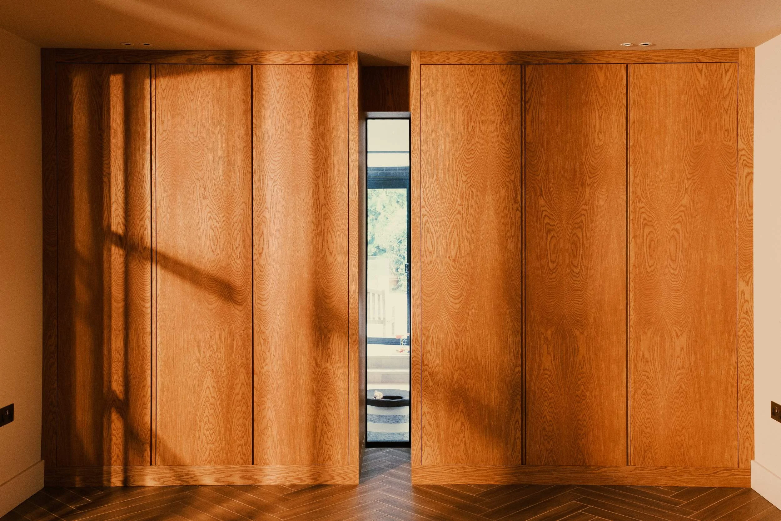 Two made to measure cupboards made from stained oak veneered boards. The cupboards are a mid century design with finger pull handles molded into the doors.
