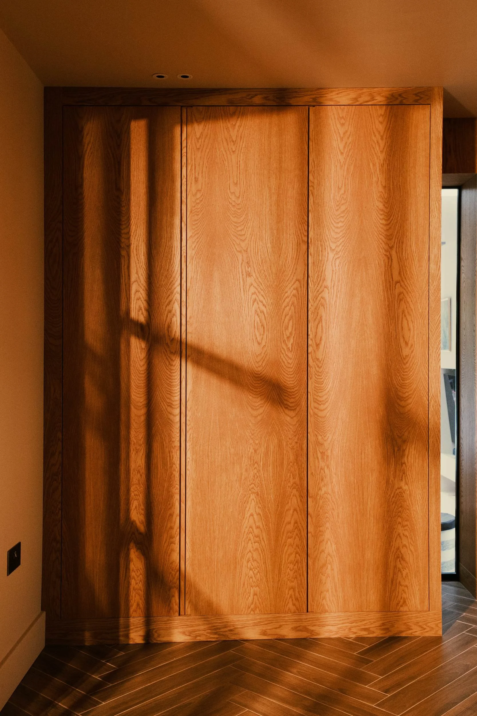 A made to measure fitted cupboard in a mid century style, made from stained oak veneered boards.