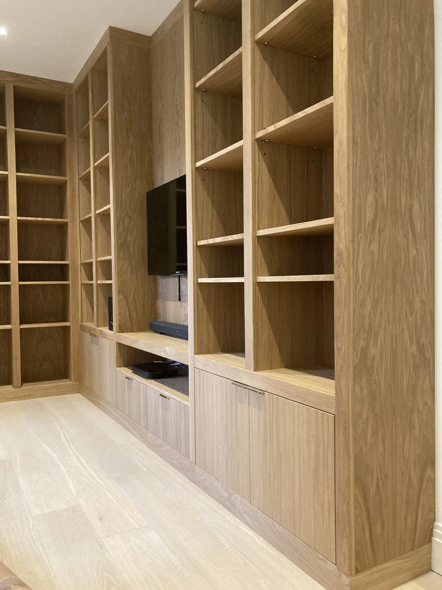 Close up of a made to measure bespoke media unit made from oak veneered boards and solid oak. Media unit consists of cupboards and adjustable shelving.