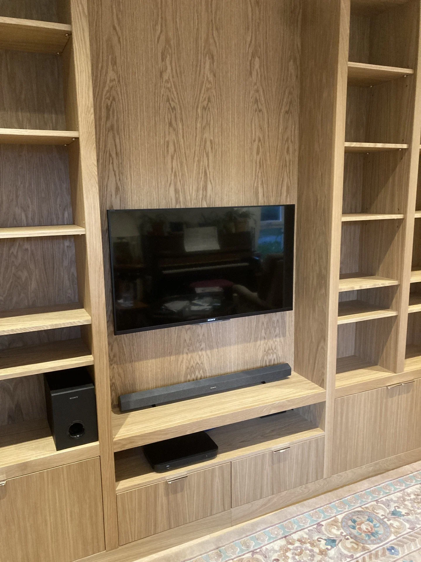 Close up of a made to measure bespoke media unit made from oak veneered boards and solid oak. Media unit consists of cupboards, adjustable shelving and a space where the TV is mounted.