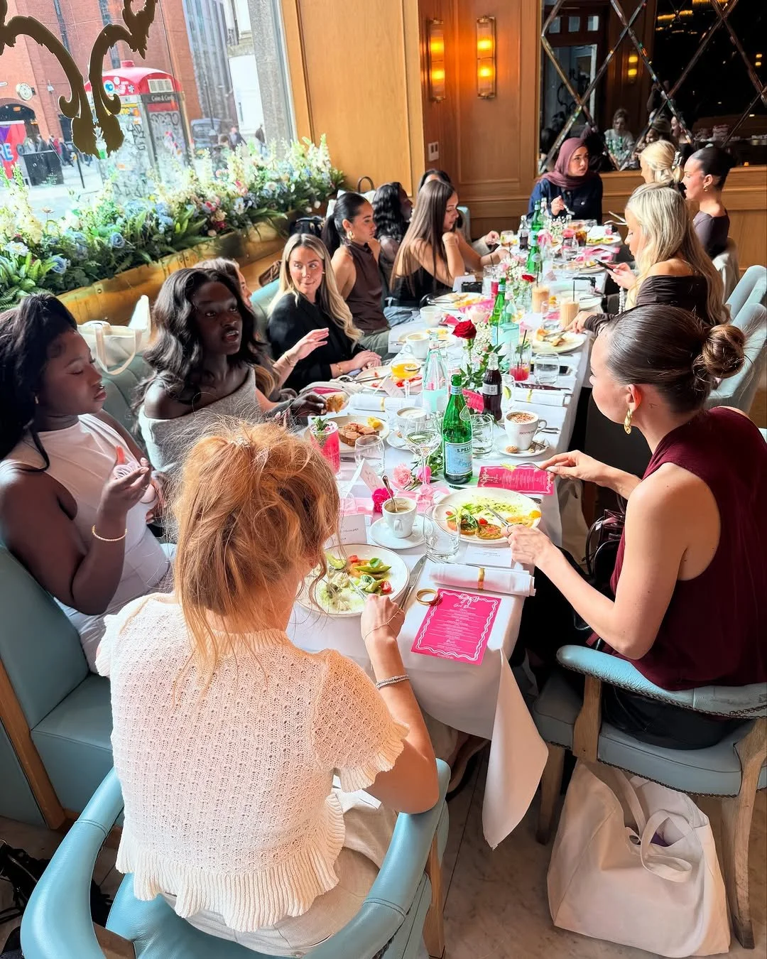 Women of diverse backgrounds sitting at a decorated dining table during a social gathering or celebration in a restaurant.