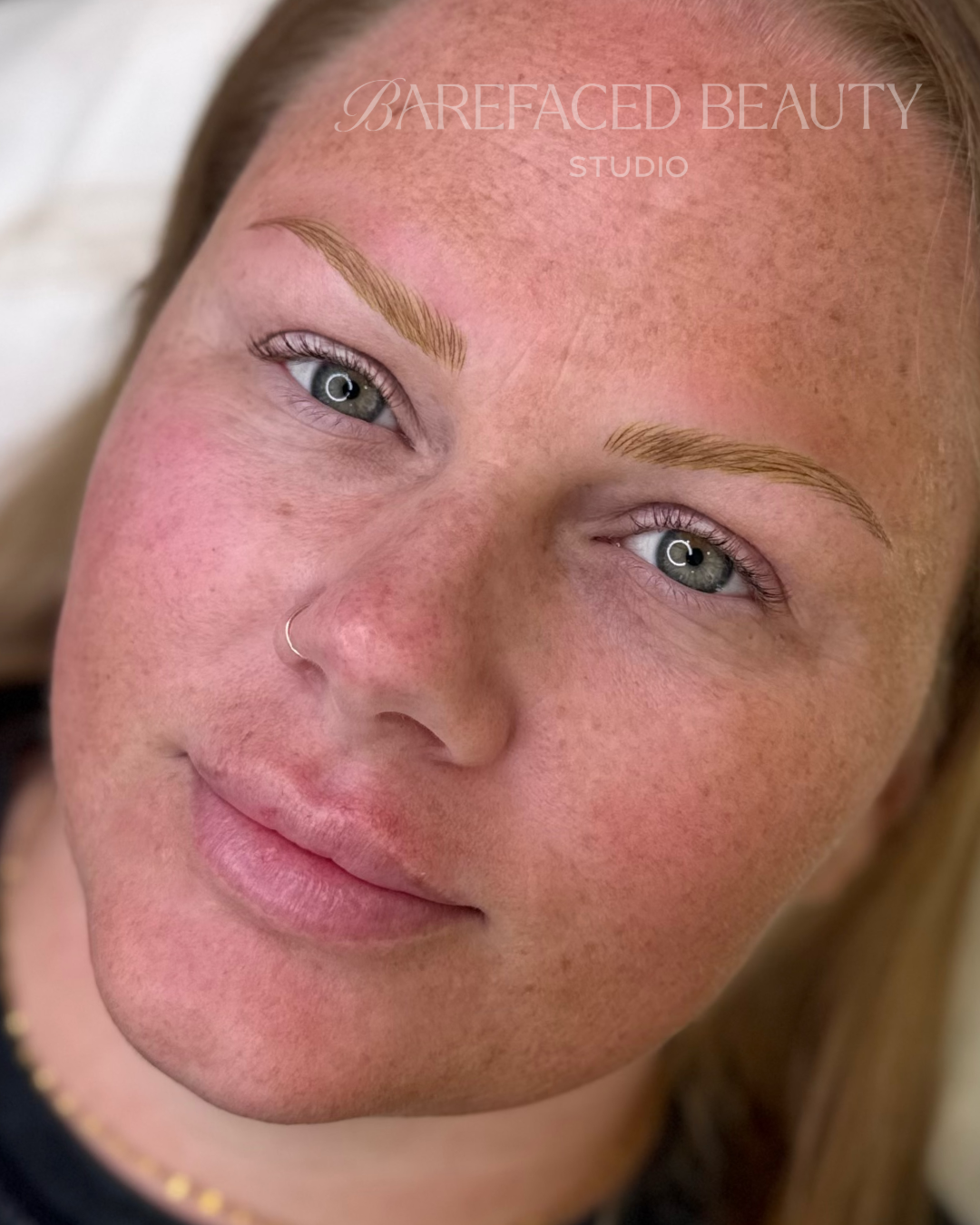 girl with freckles has nose ring and realistic eyebrow tattoo
