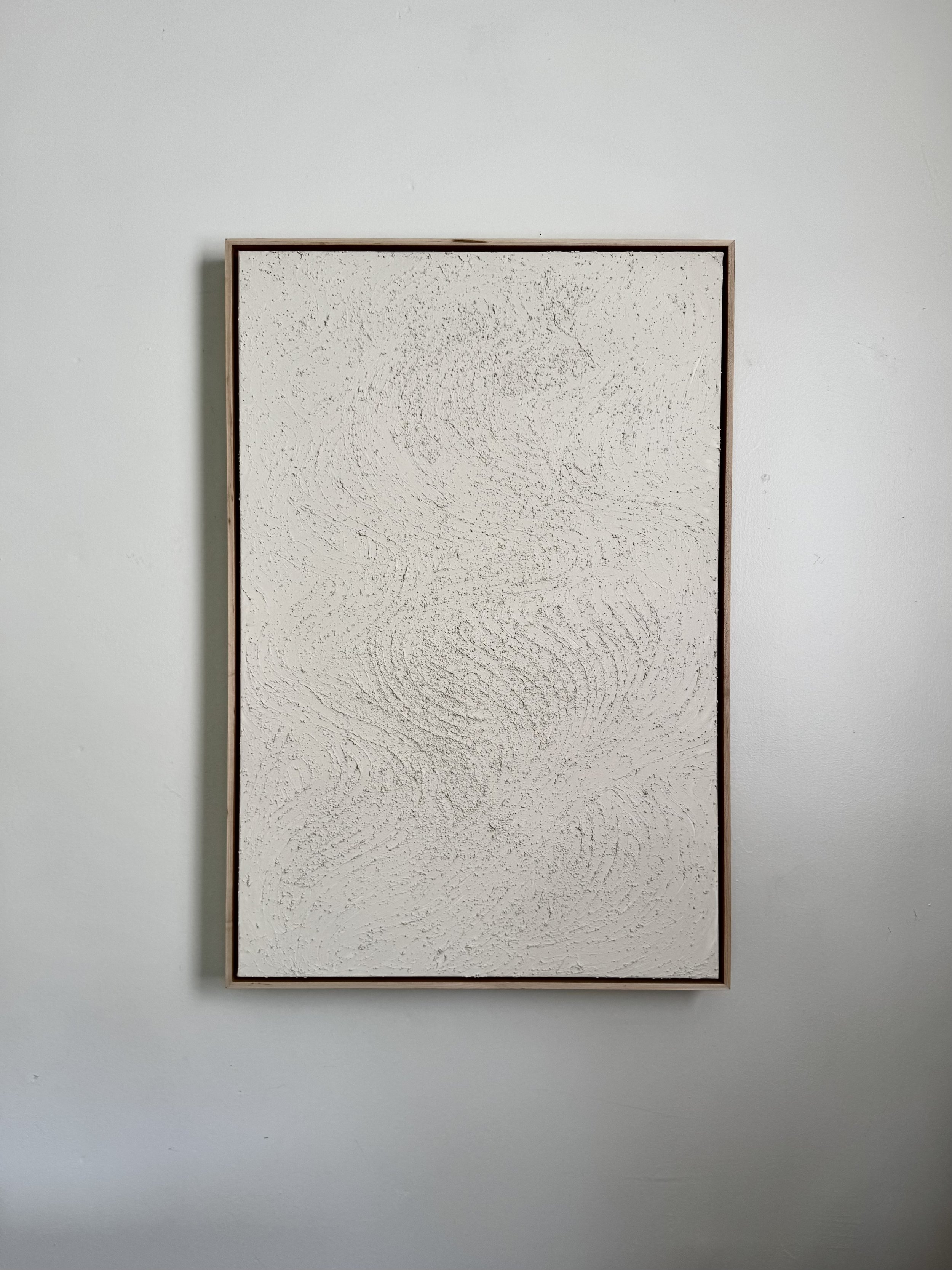 A light colored artwork, hung on the wall, framed and on canvas.