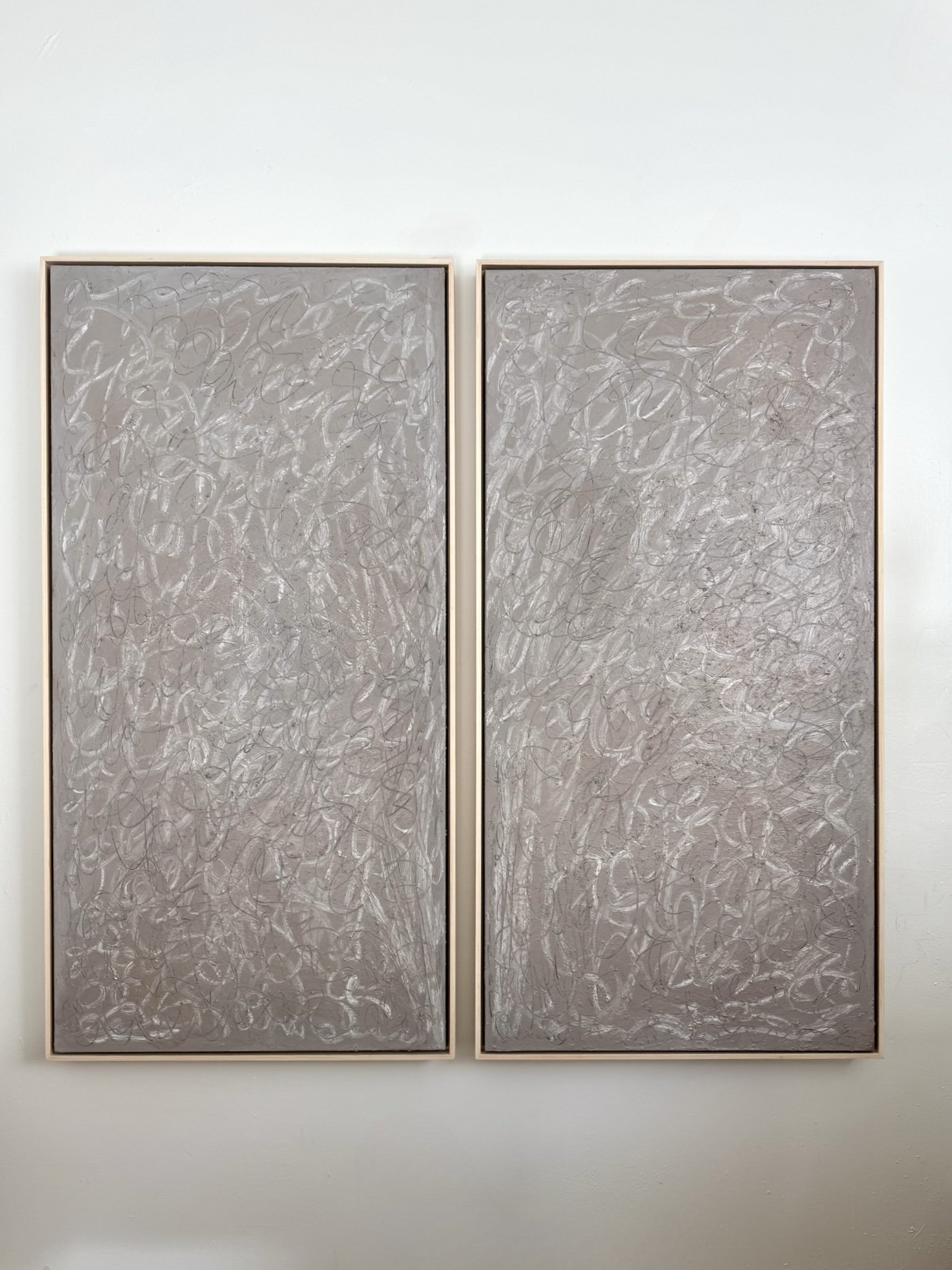 Two dark colored art pieces, framed and hung on the wall.
