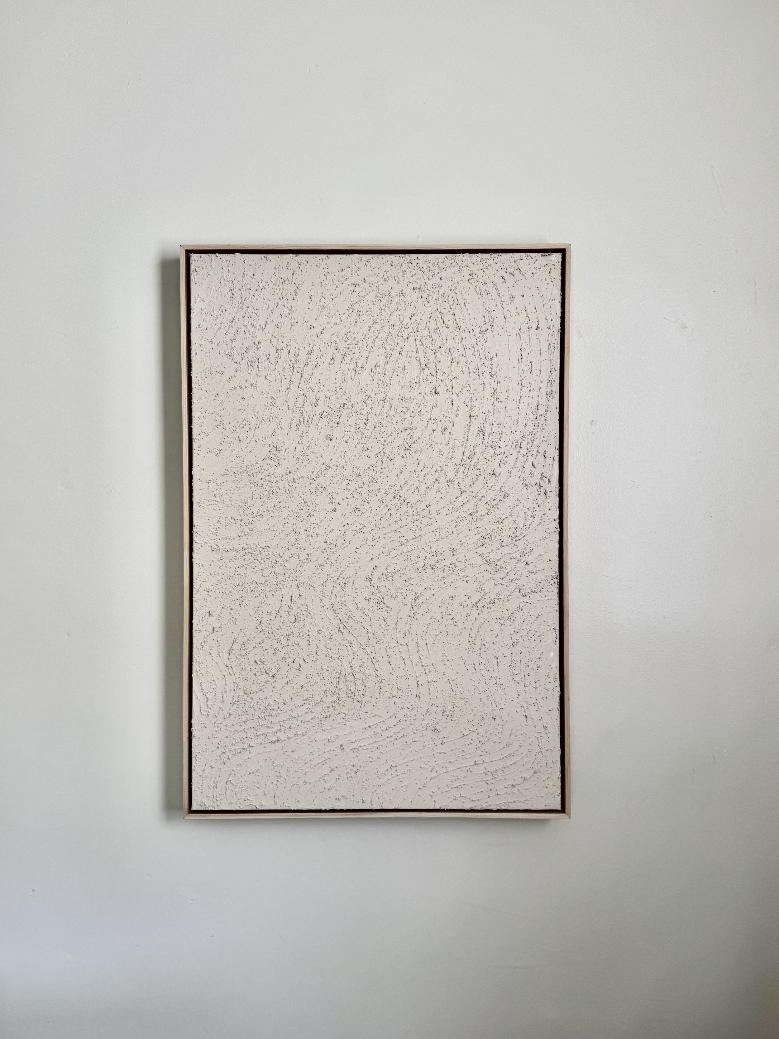 A light colored art piece, hung on the wall, framed and on canvas.