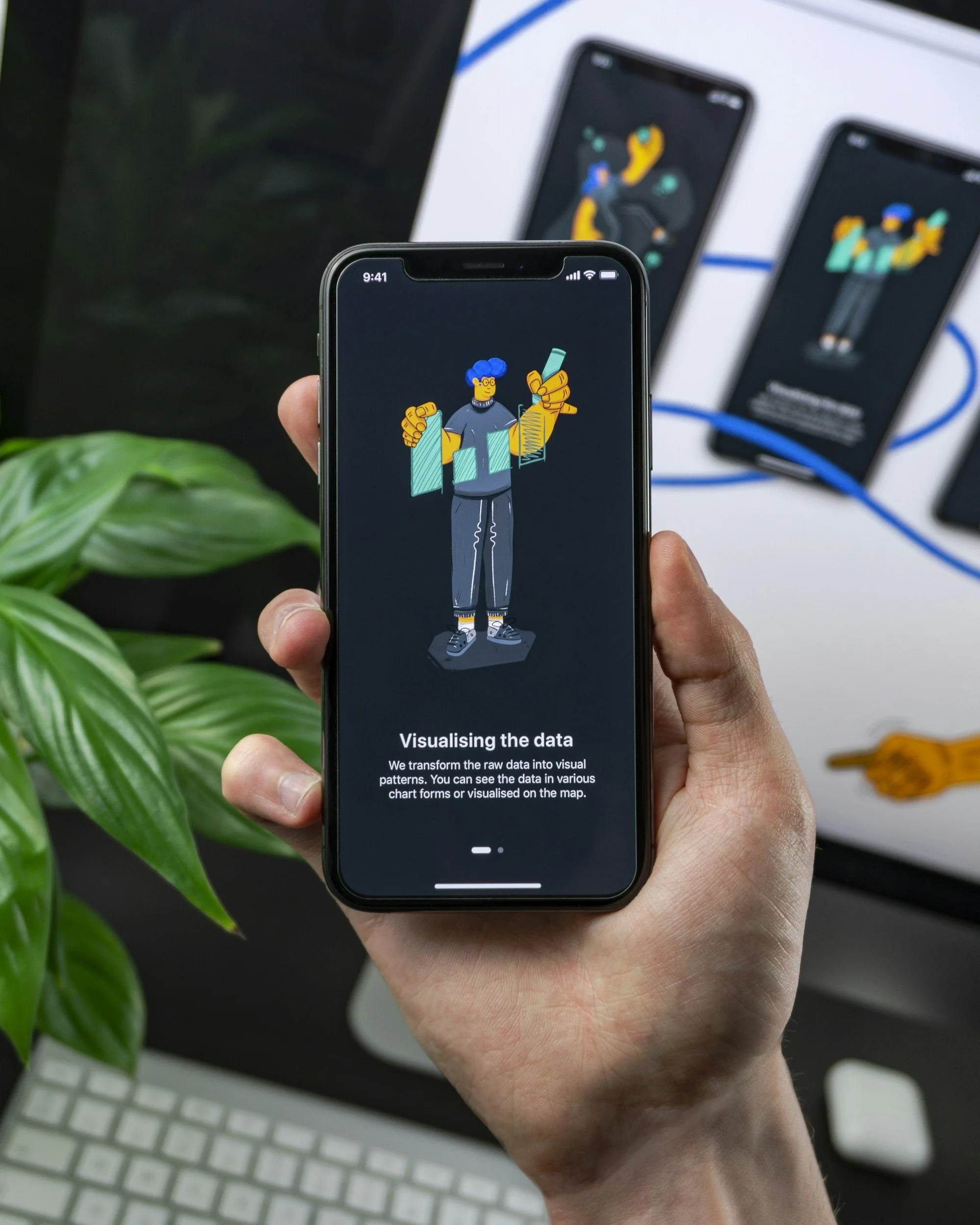 Close-up of a person holding a smartphone displaying a digital cartoon character with blue hair, glasses, and yellow hands, illustrating data visualization with a bar chart and text about transforming raw data into visual patterns.