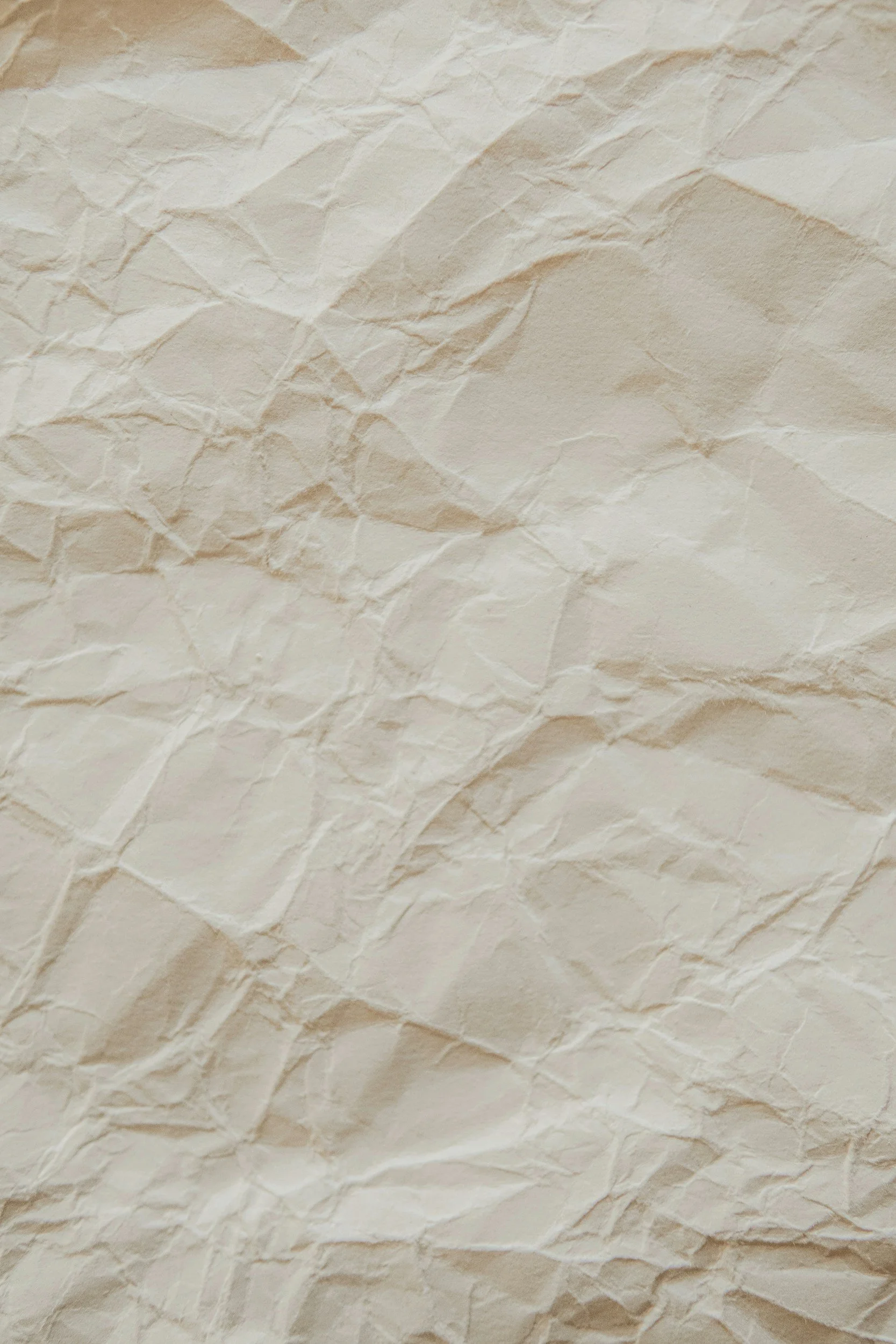 Close-up of crumpled white paper with textured surface and irregular folds.