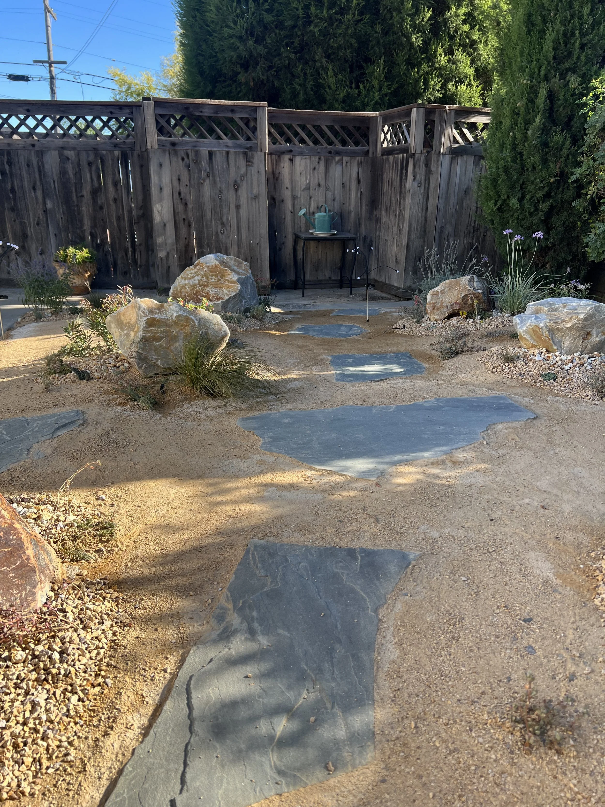 drought resistant backyard remodel. Flagstones placed in dg surrounded by plants and boulders