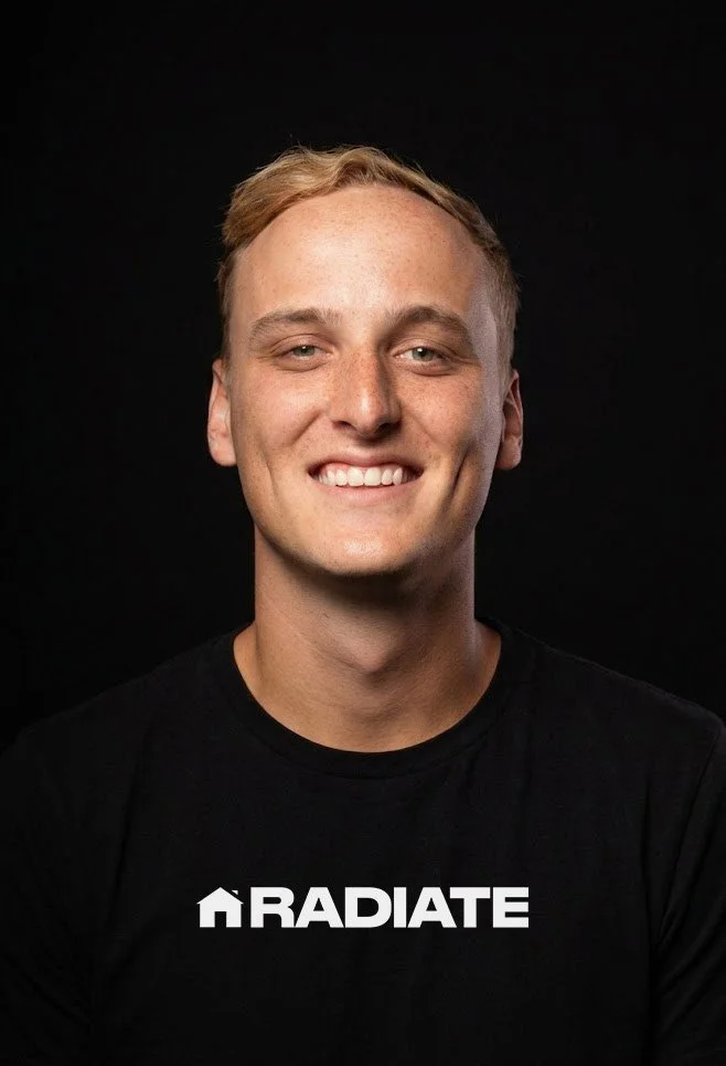 A smiling young man with light skin, freckles, short blonde hair, and blue eyes, wearing a striped t-shirt, posed against a plain white background.