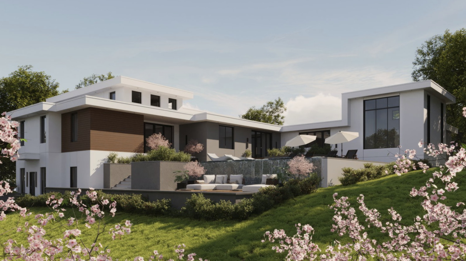 Modern multi-story house with large windows, a water feature, outdoor seating, and pink flowering trees in the yard.