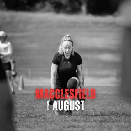 A woman on a grassy field about to kick a football, with another woman in the background, and red text reading 'Macclesfield 1 August'.