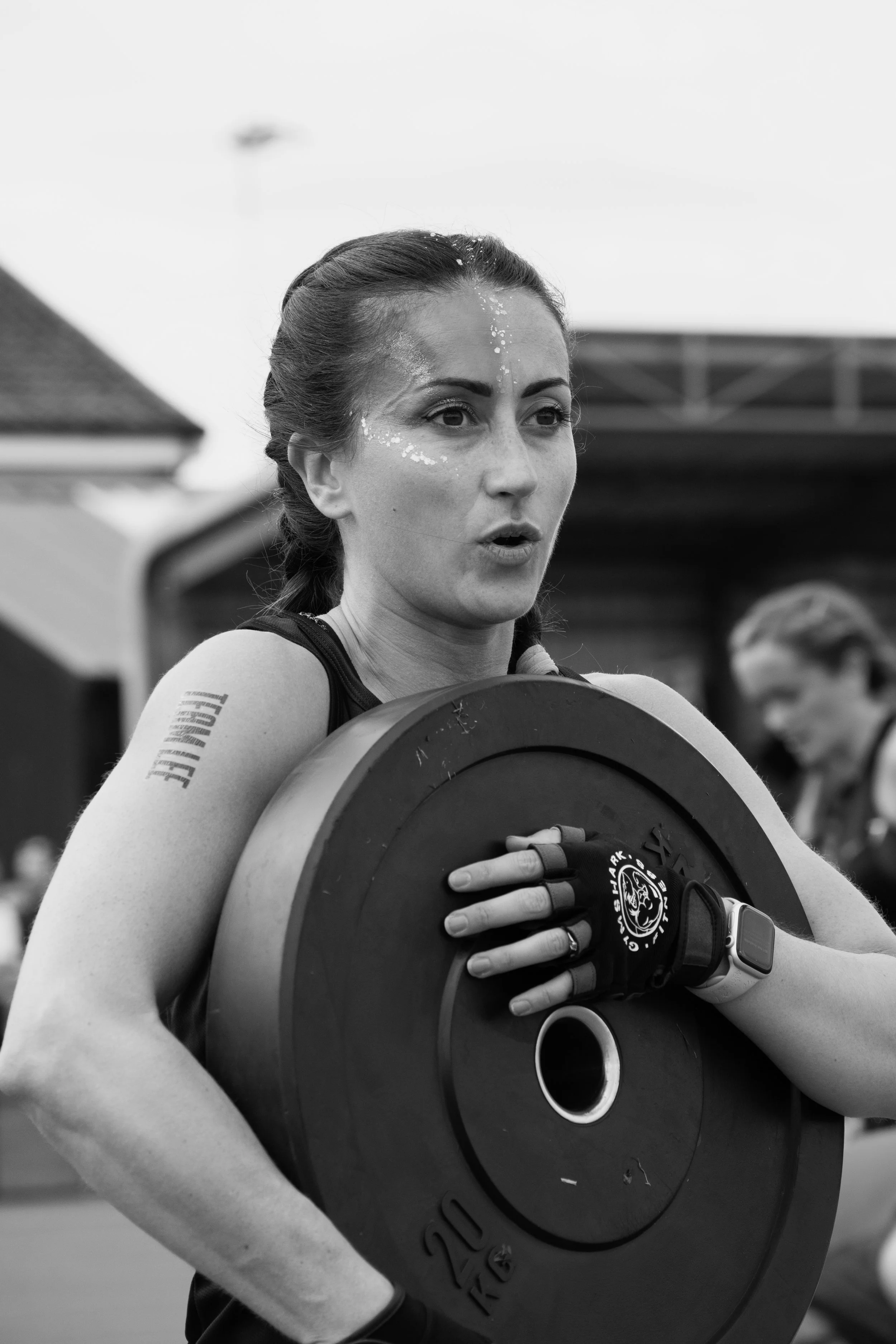 A woman lifting a large weight plate during a fitness event