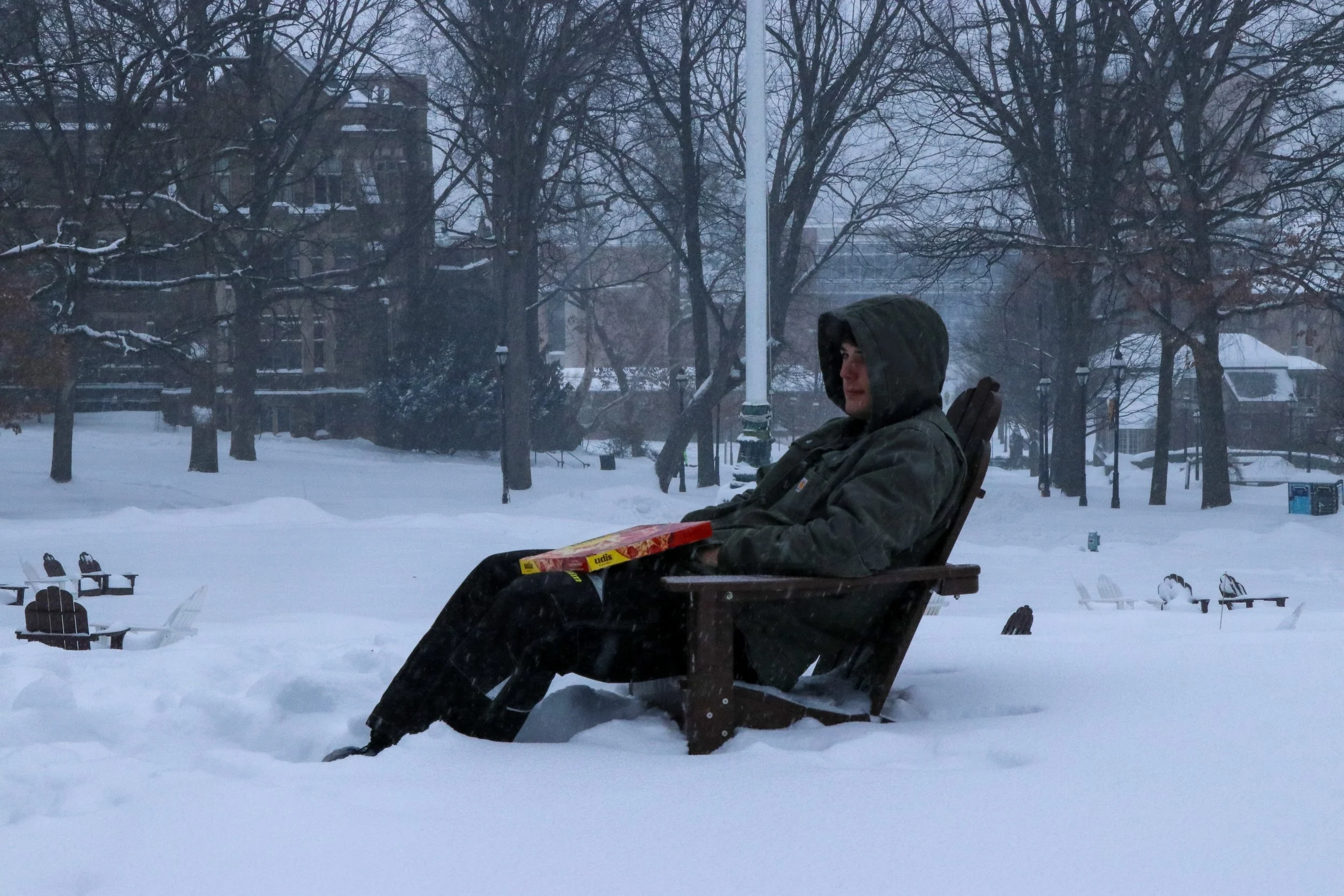 A student sits on a snow-covered lawn chair outside Lehigh’s Clayton University Center. Students built ski and sled jumps following Sunday’s winter storm. (Luke Kaiser/B&W Staff)