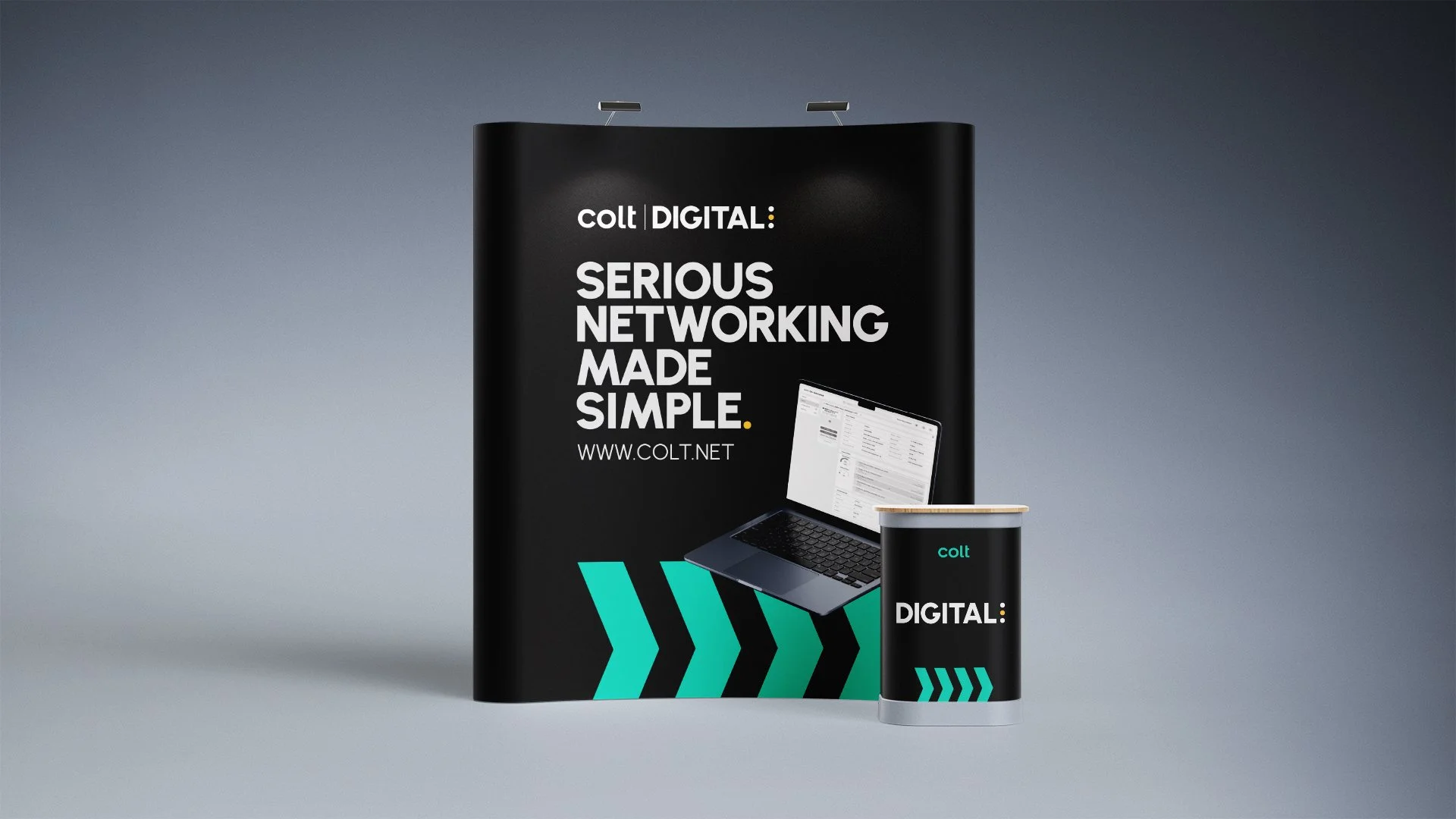 Colt Digital curved promotional stand, showing laptop with a Colt portal on screen, in front of stand is a branded podium table