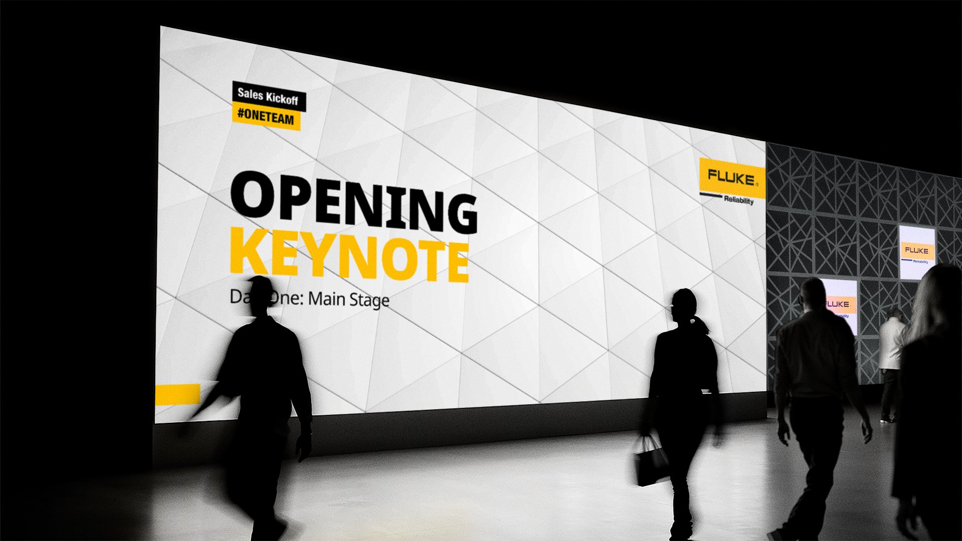 A huge LED screen showing the opening slide for the opening keynote. People walking past the screen in silhouette.