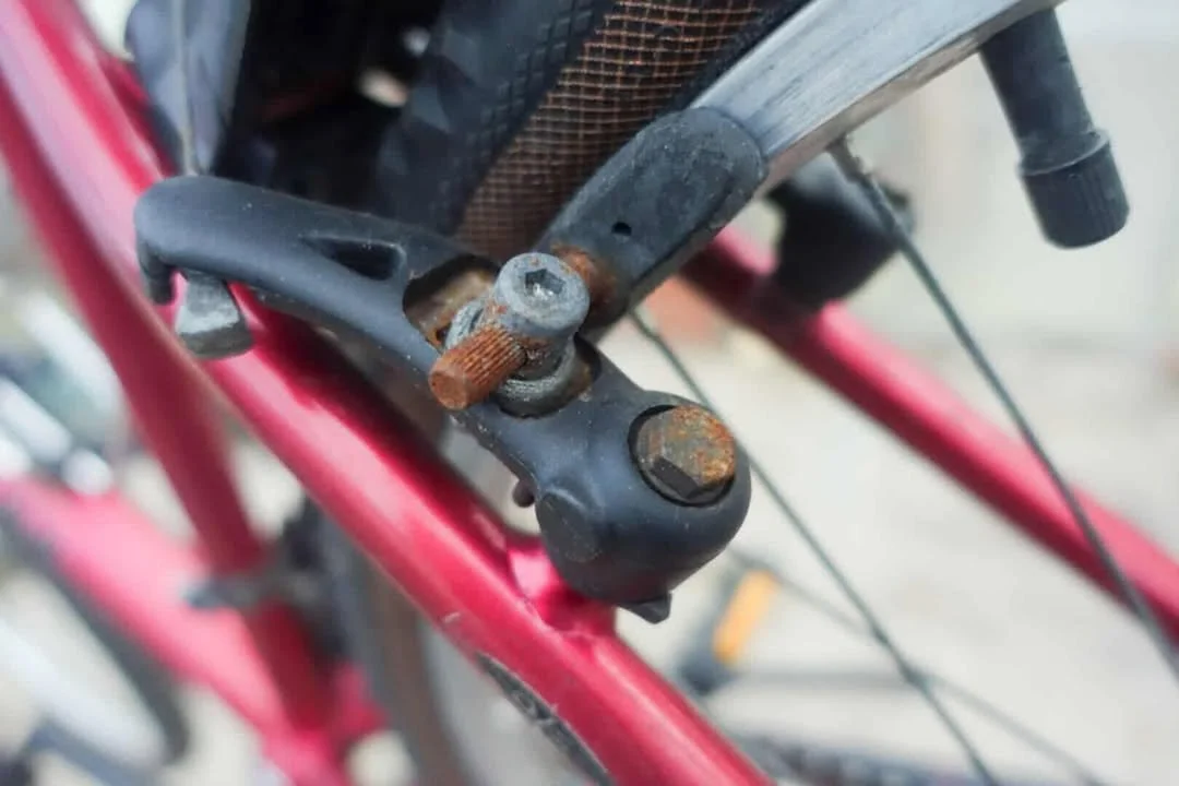Close-up of a rusty bicycle seat post clamp on a pink bicycle frame.