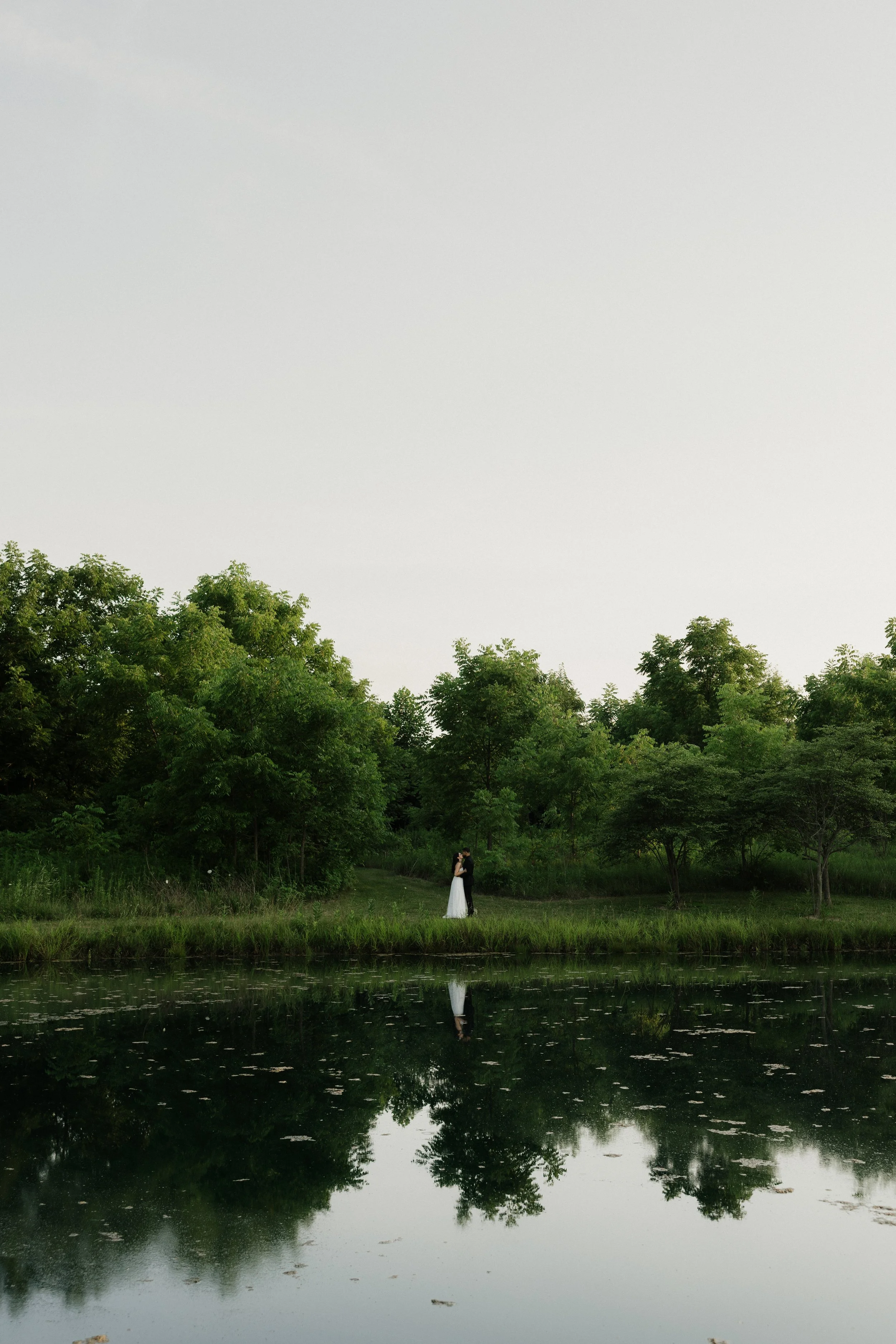 bride and groom across lake