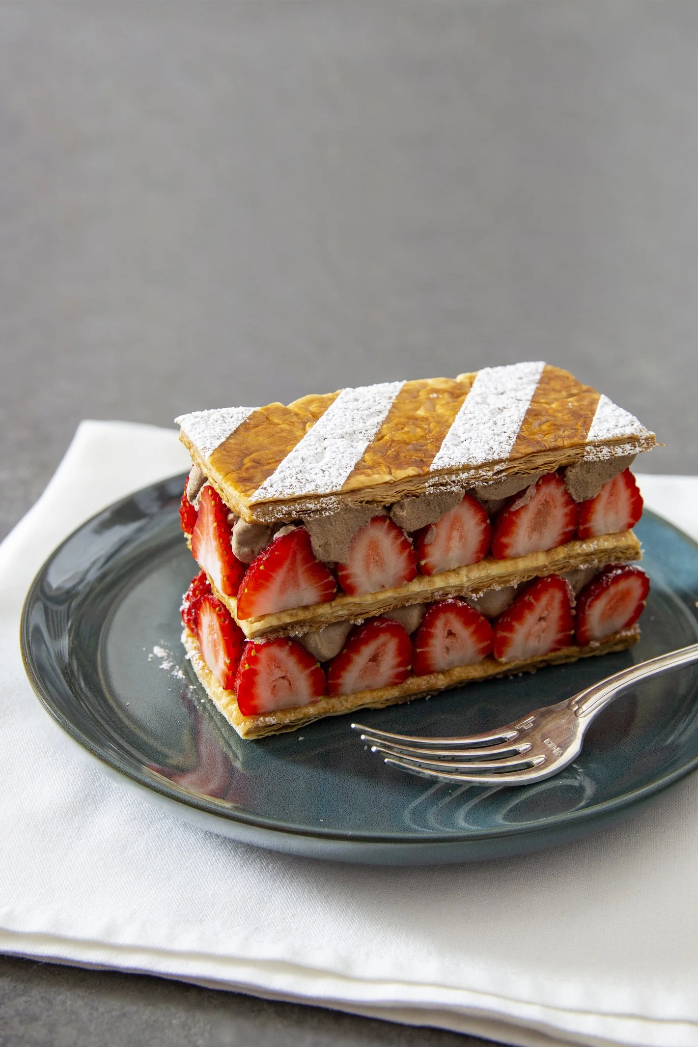 Chocolate and strawberry mille-feuille beautifully plated on blue serving dish