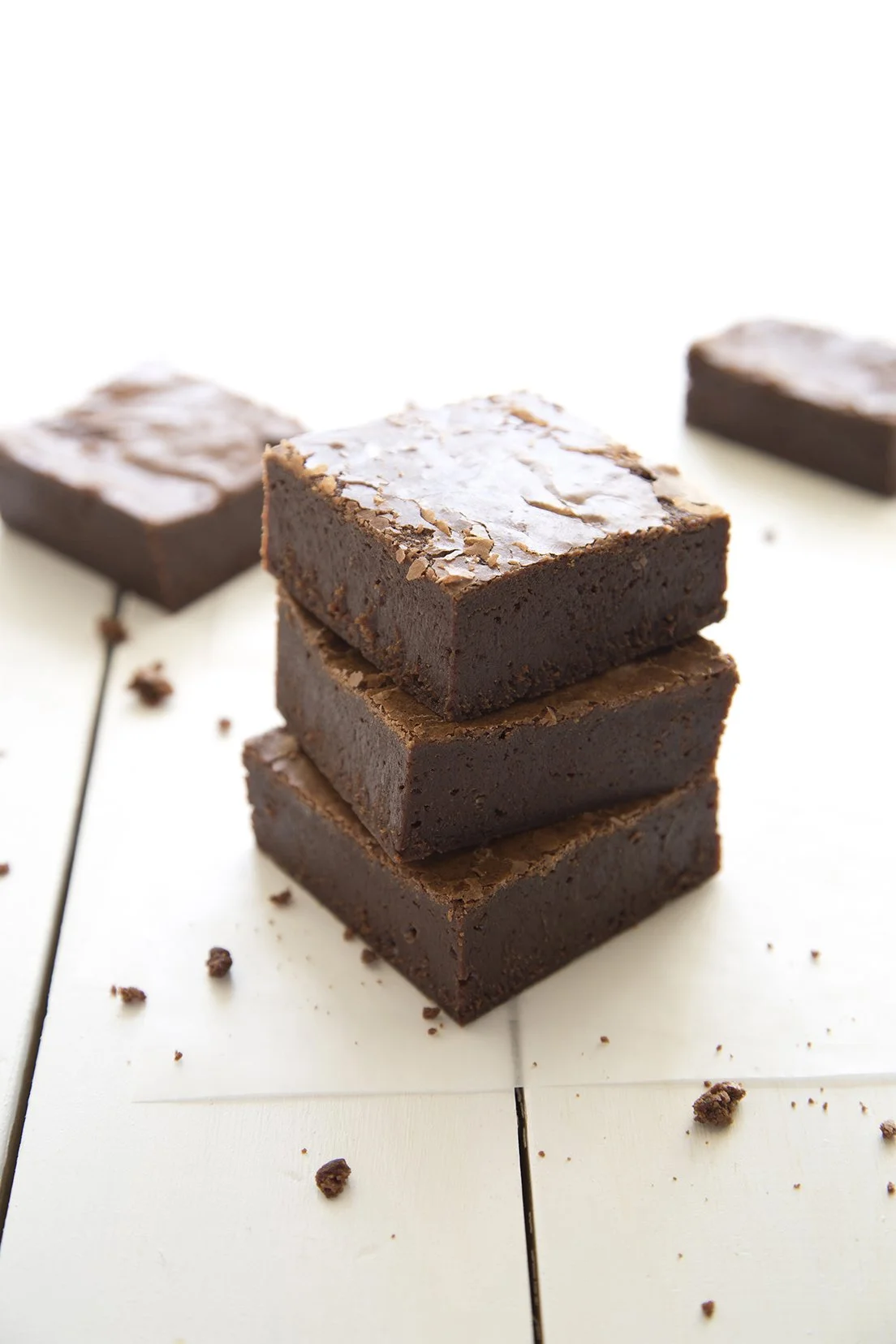 Dark chocolate decadent brownie, piled on top of one another on a white wooden table, natural light food photography