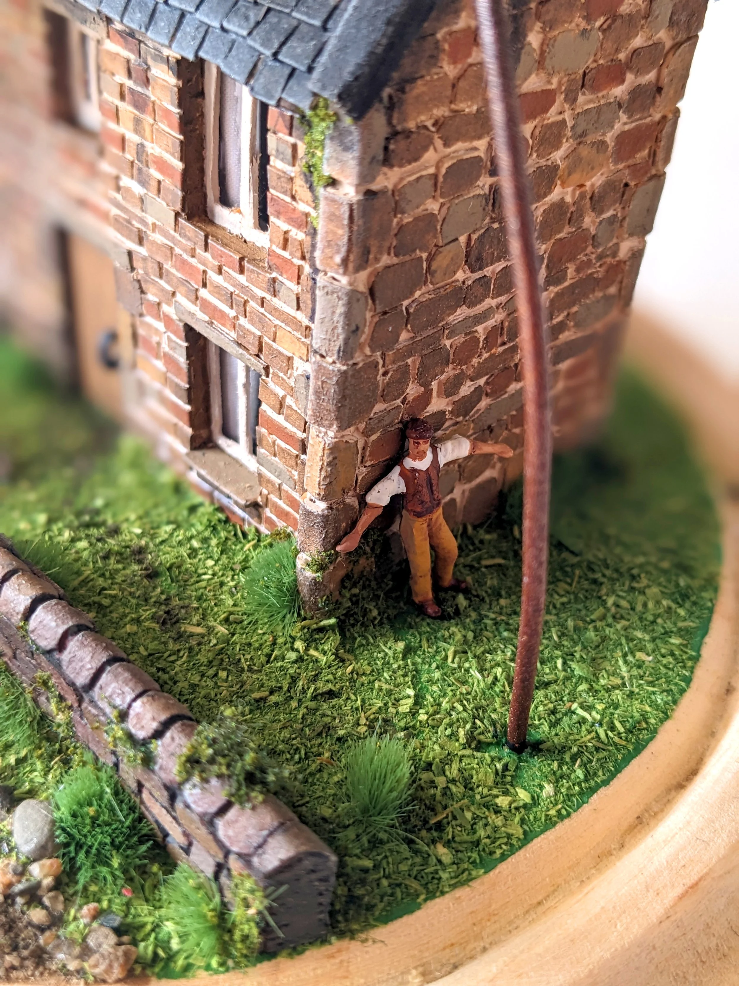 Miniature scale model of a martian machine attacking a house, with a person hiding