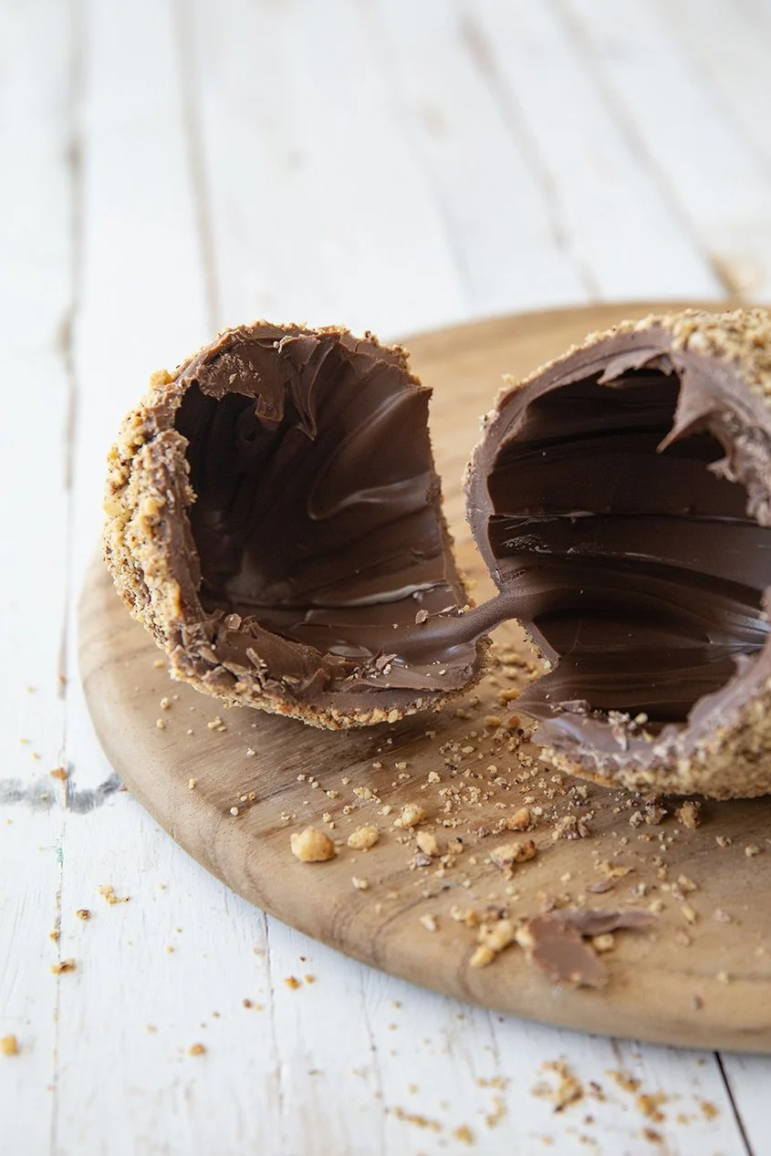 Crunchy chocolate egg plsit open to show a flowy hazelnut spread interior