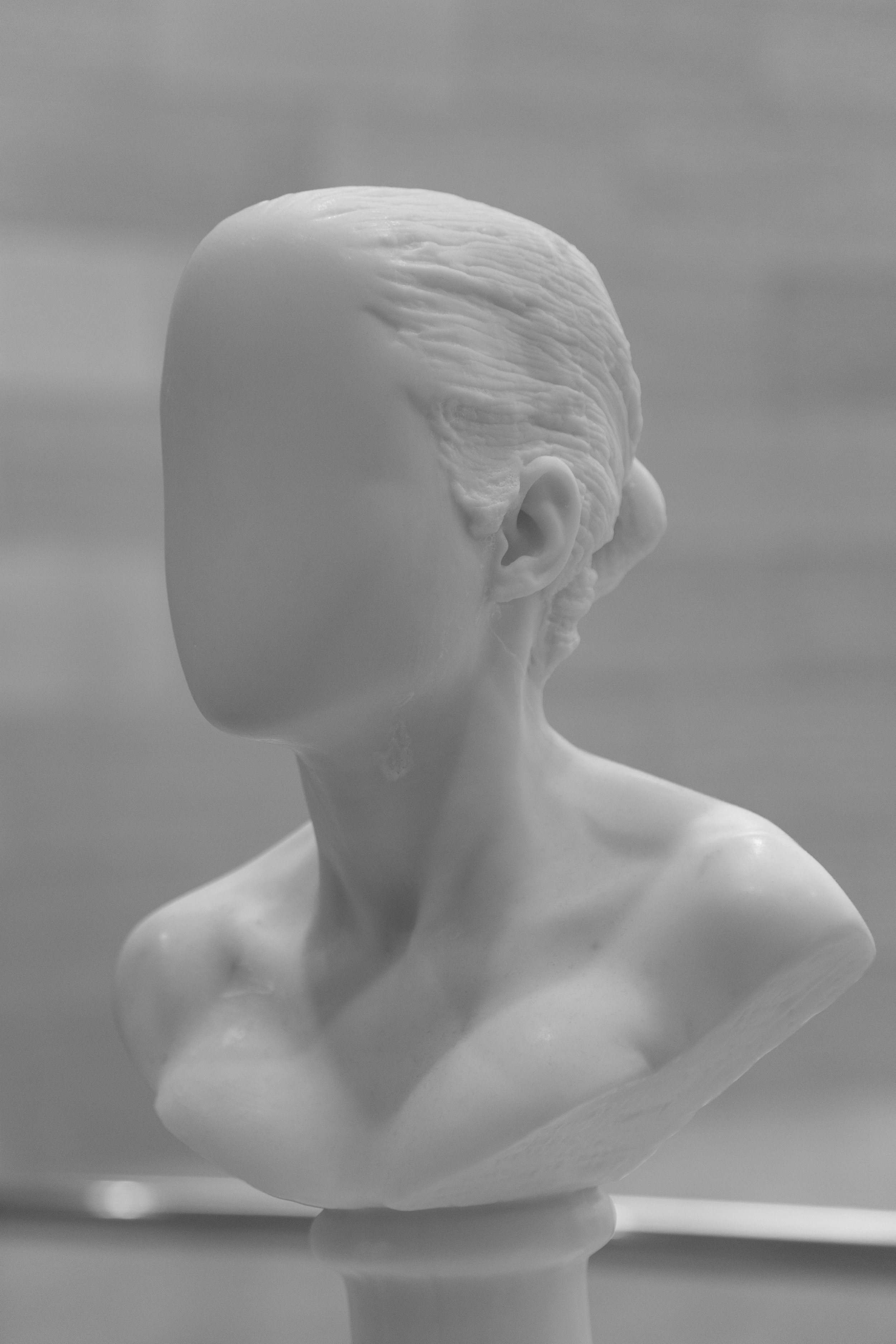 A stone statue of a woman with a blank face, elegant composition, white statue in museum, photo by Lionel May