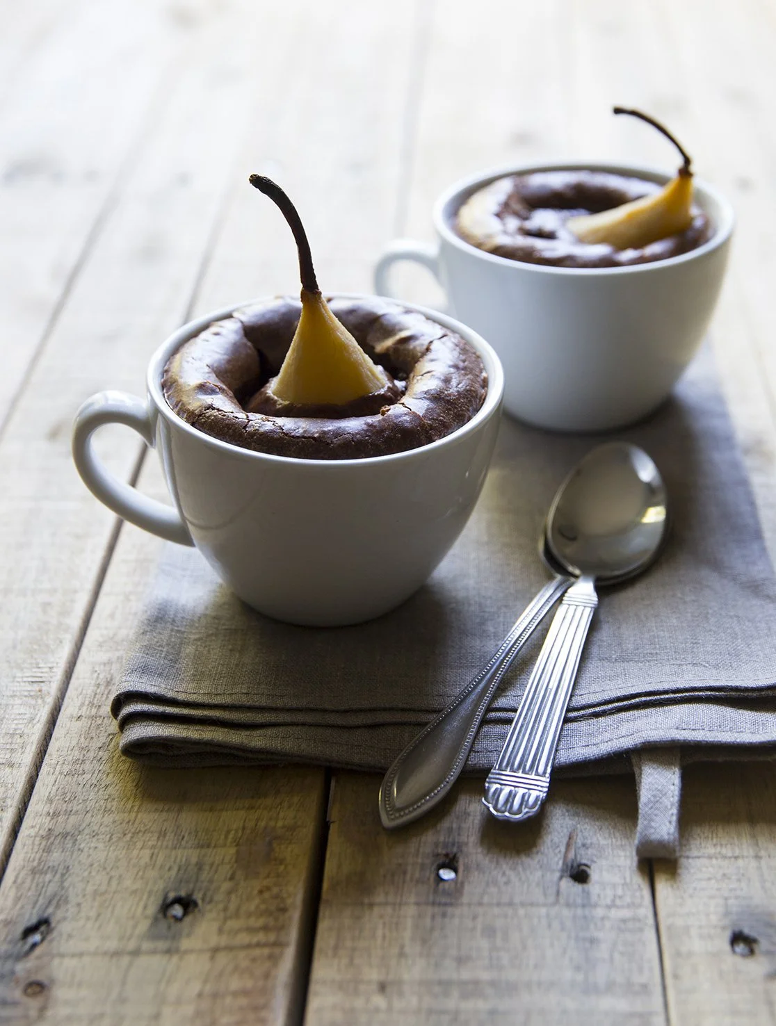 Beautiful brownies with whole poached pears stuck inside, baked in porcelain cups. 