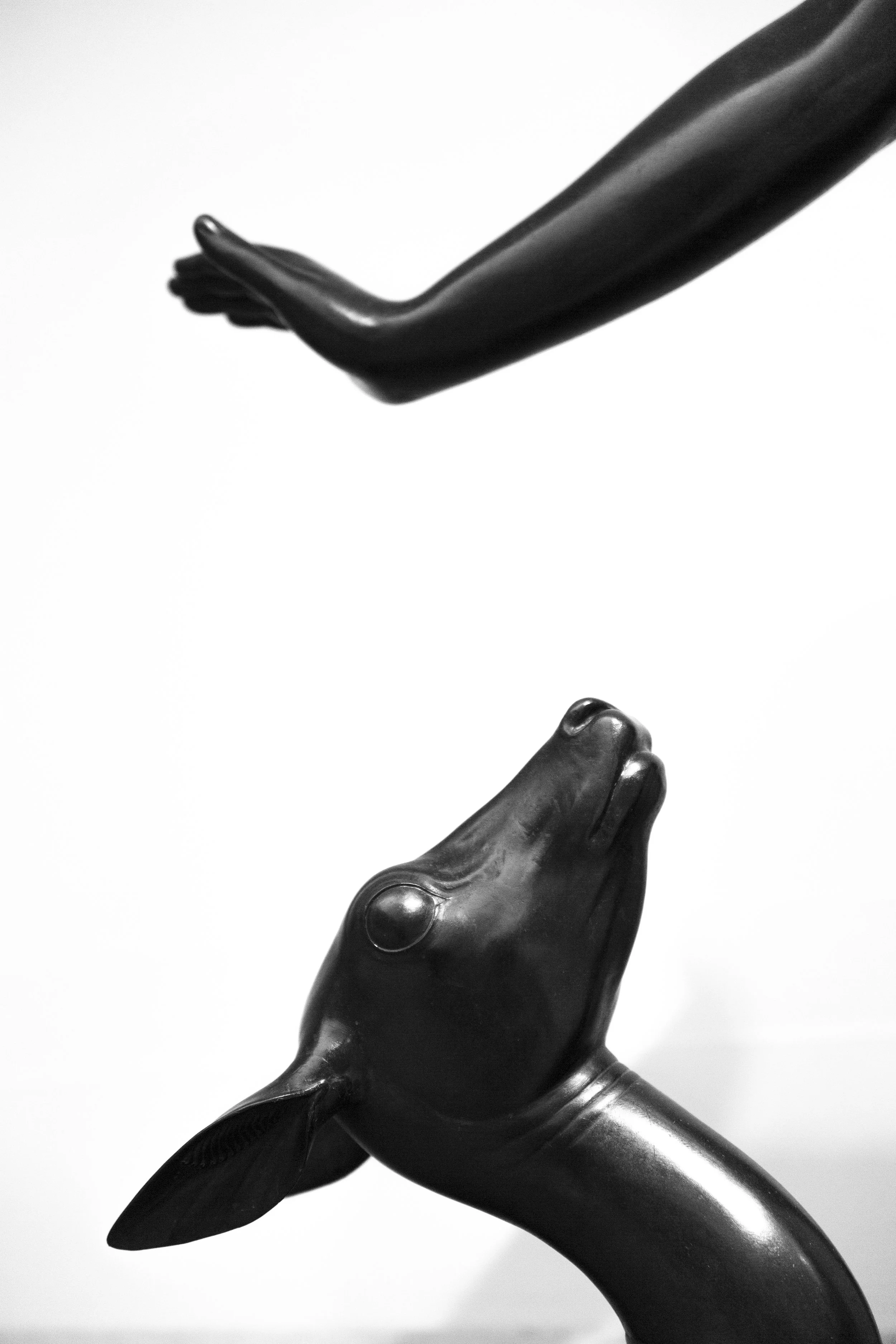 Graphic composition, black and white photo of a statue, close-up of hand and deer against white background. 