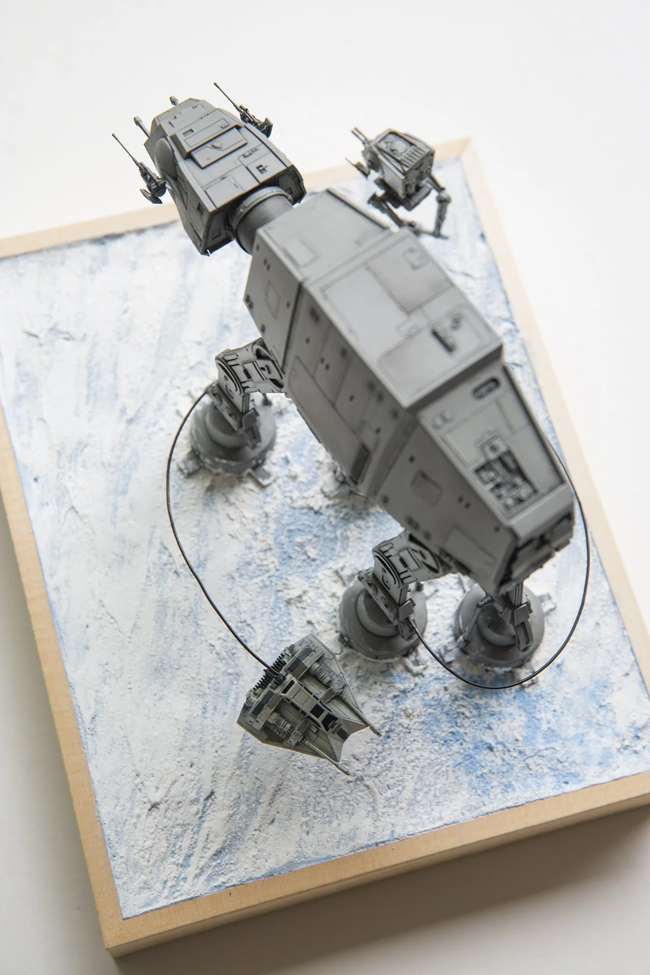 Overhead view of a custom diorama from Star Wars, showing a snowspeeder circling an AT-AT