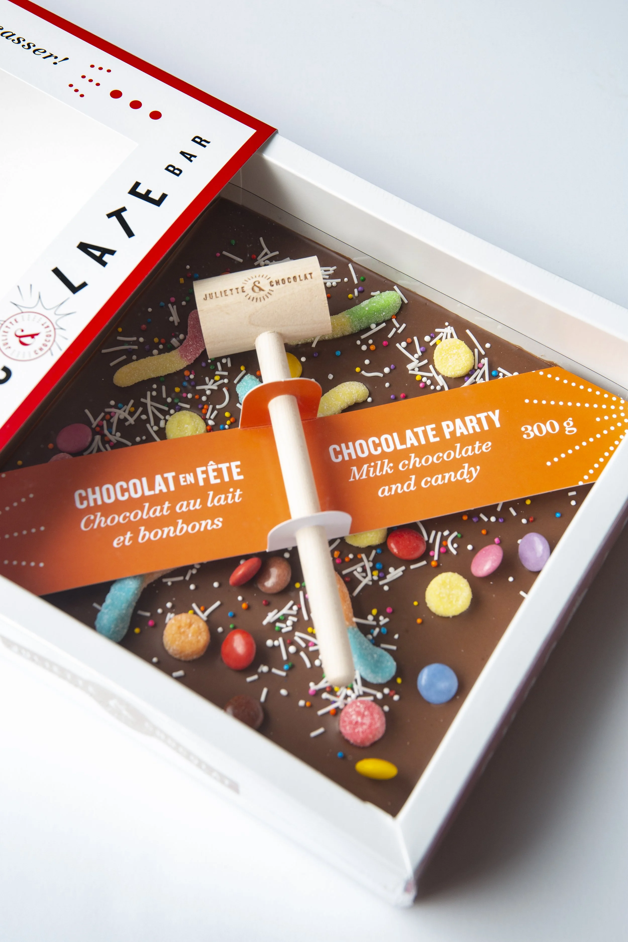 Large square chocolate bar with wooden mallet in sliding box.