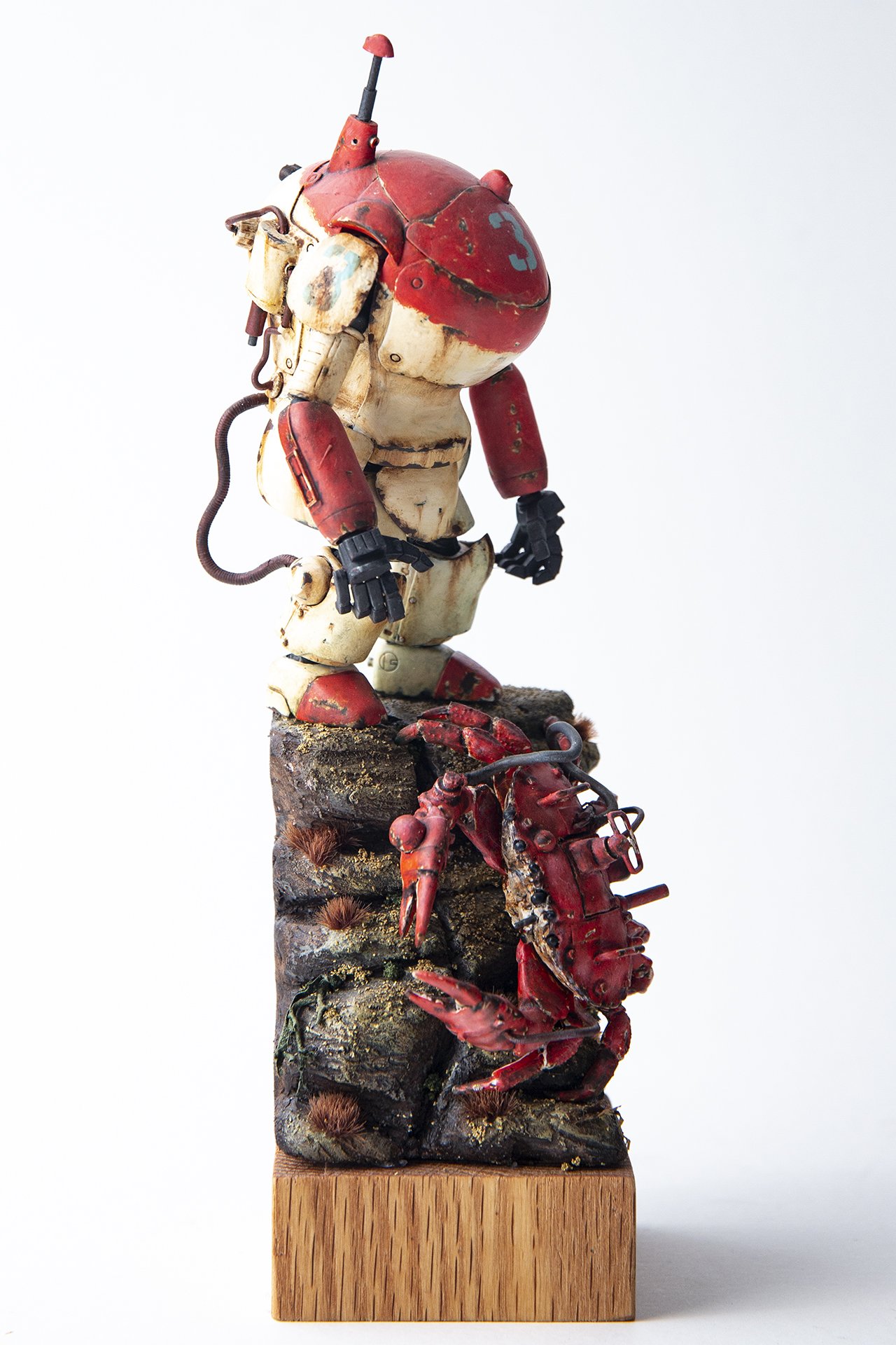 Plastic scale model of red and white Maschinen Krieger mechanical suit on custom base. 