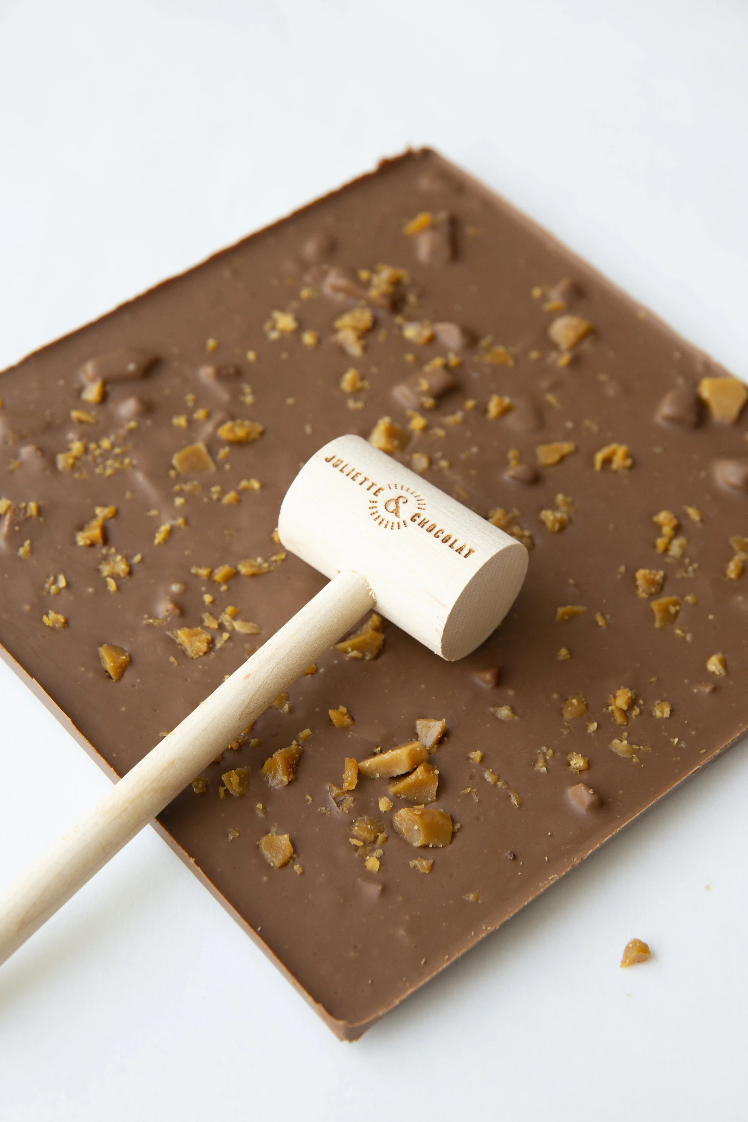 Small wooden hammer with the name Juliette & Chocolat on large milk chocolate and caramel bar. 