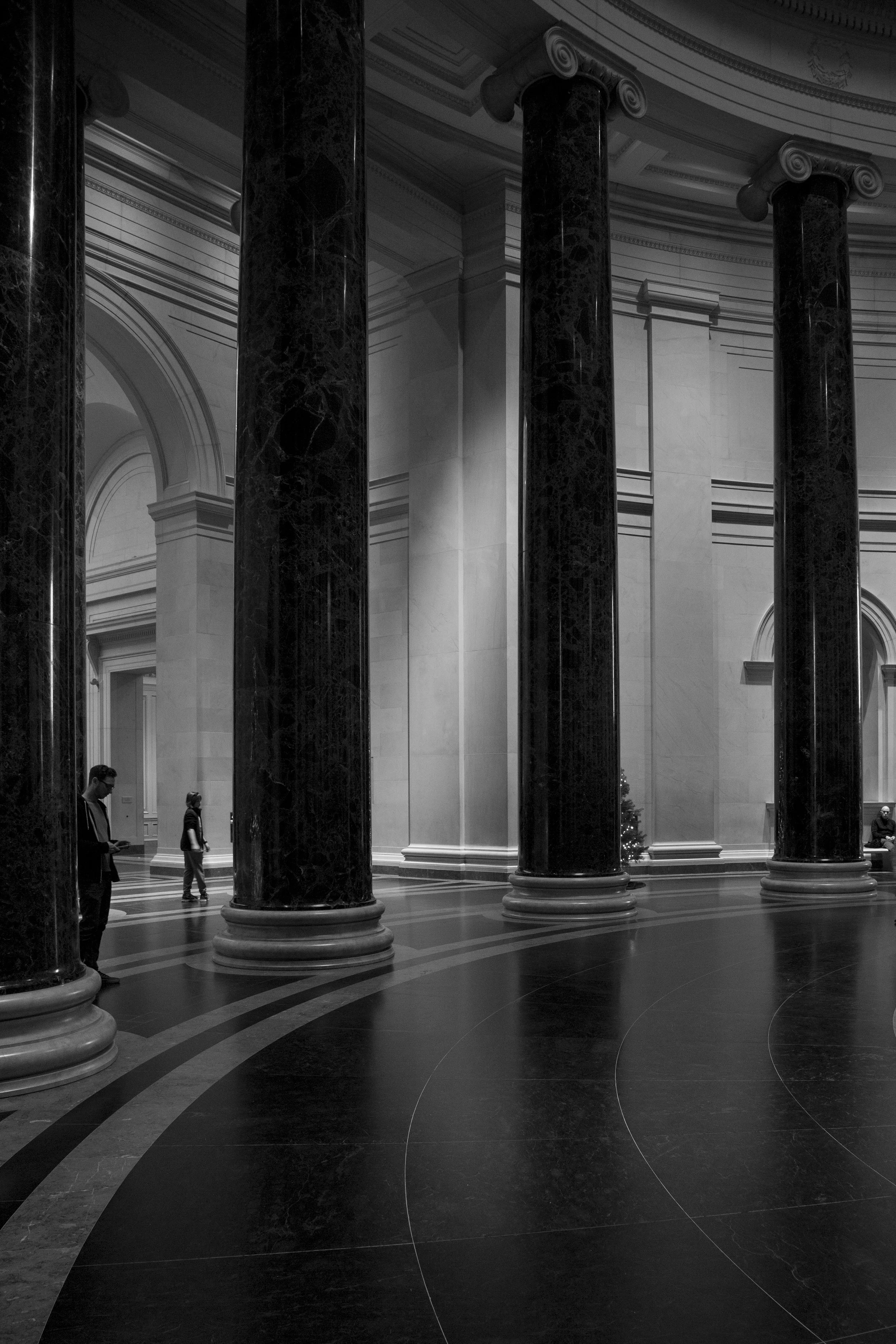 Huge columns in circular room in art musem with spectacular architecture photographed in moody black and white.  