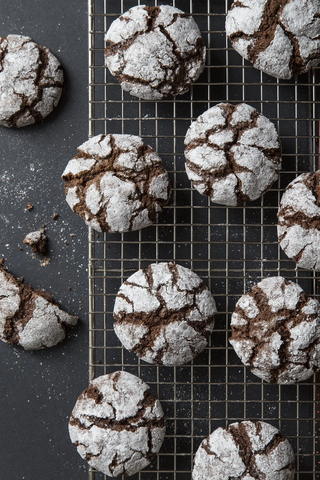 Crinckle cookies, dark chocolate and cocoa dusted with sugar, on metal sheet on dark table. 