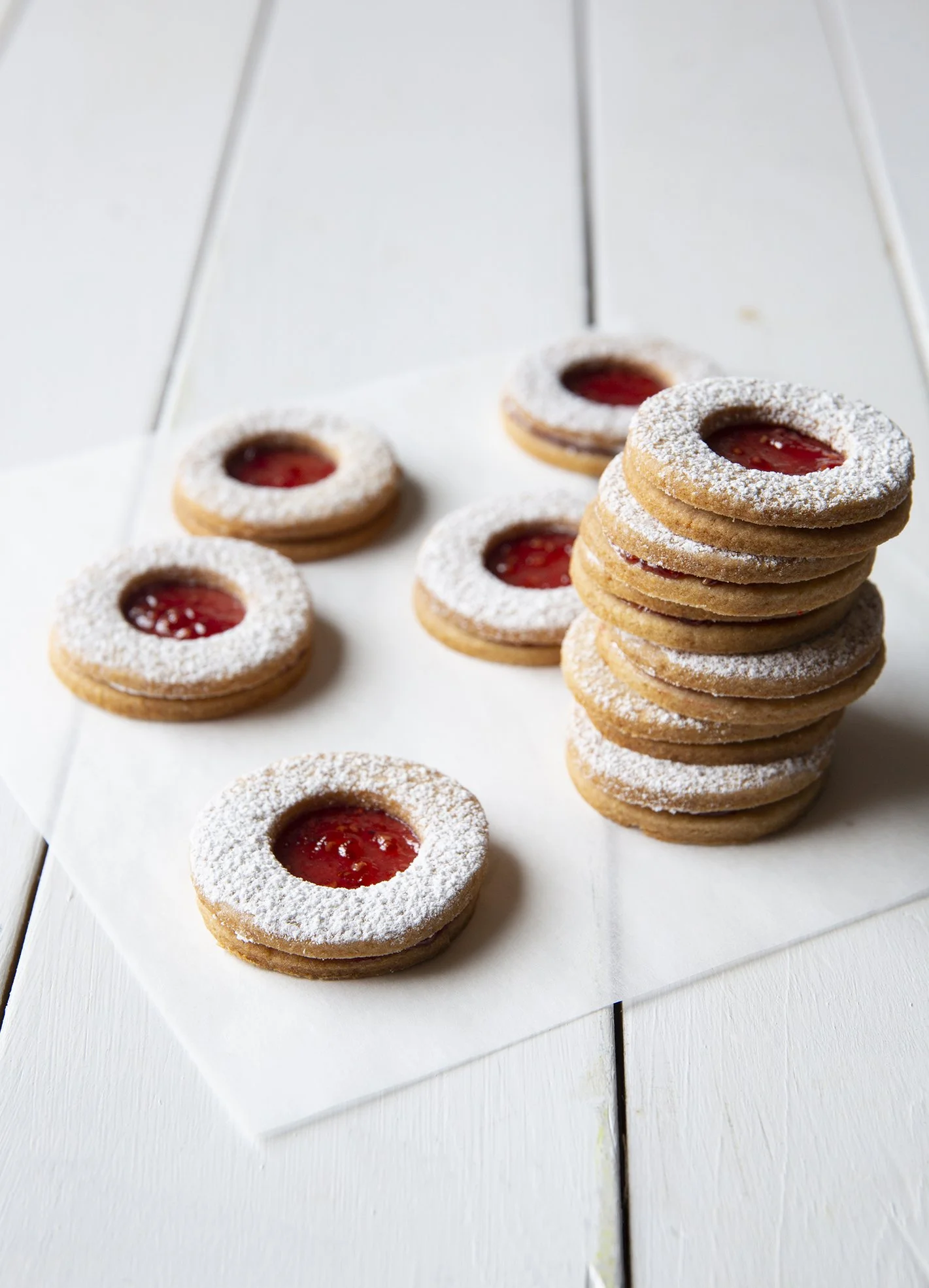 Perfectly round jam cookies, with a strawberry center, dusted with powdered sugar.