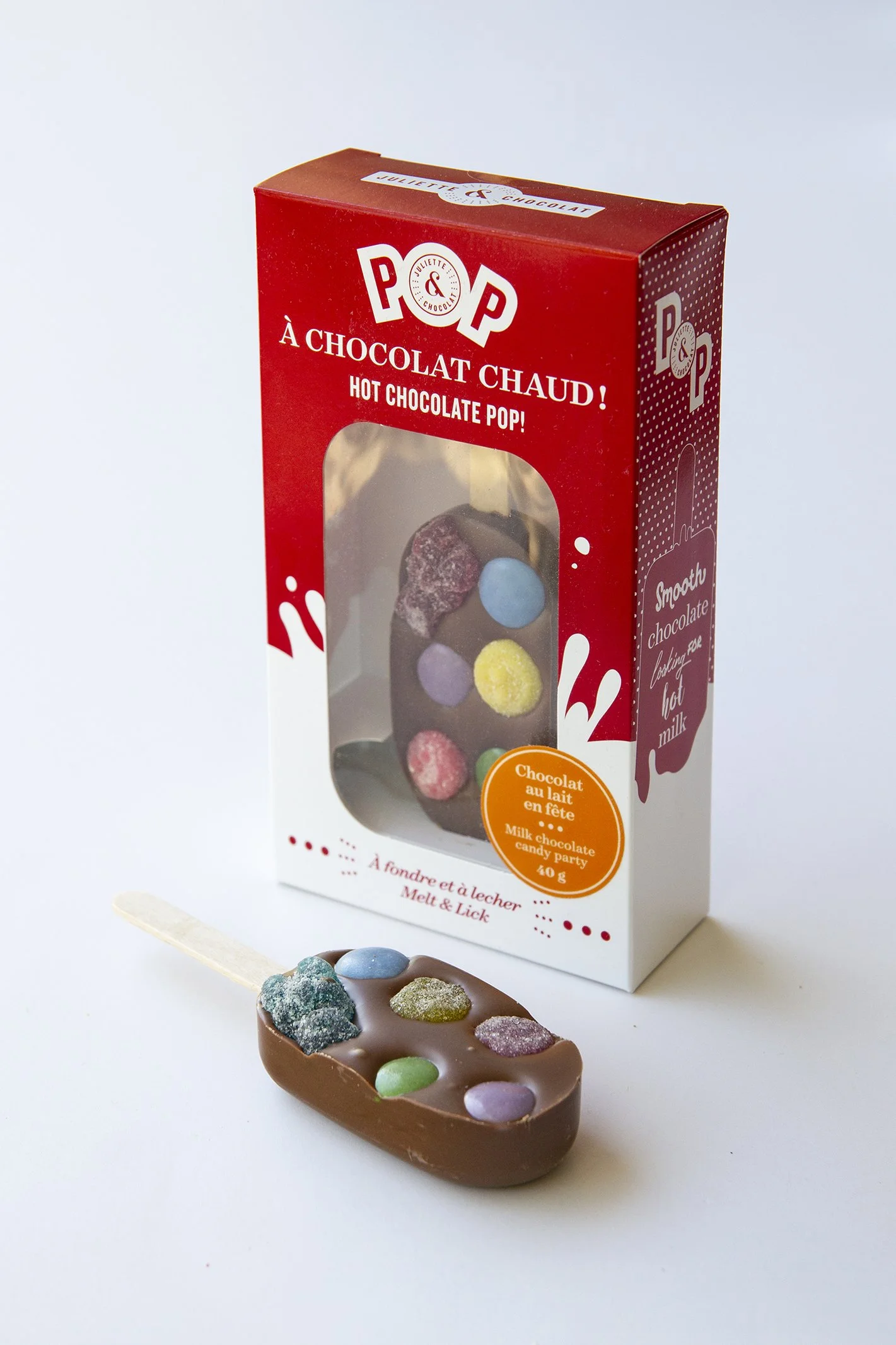 Chocolate pop for melting in hot milk, presented with another one still in its colorful box with transparent window. 