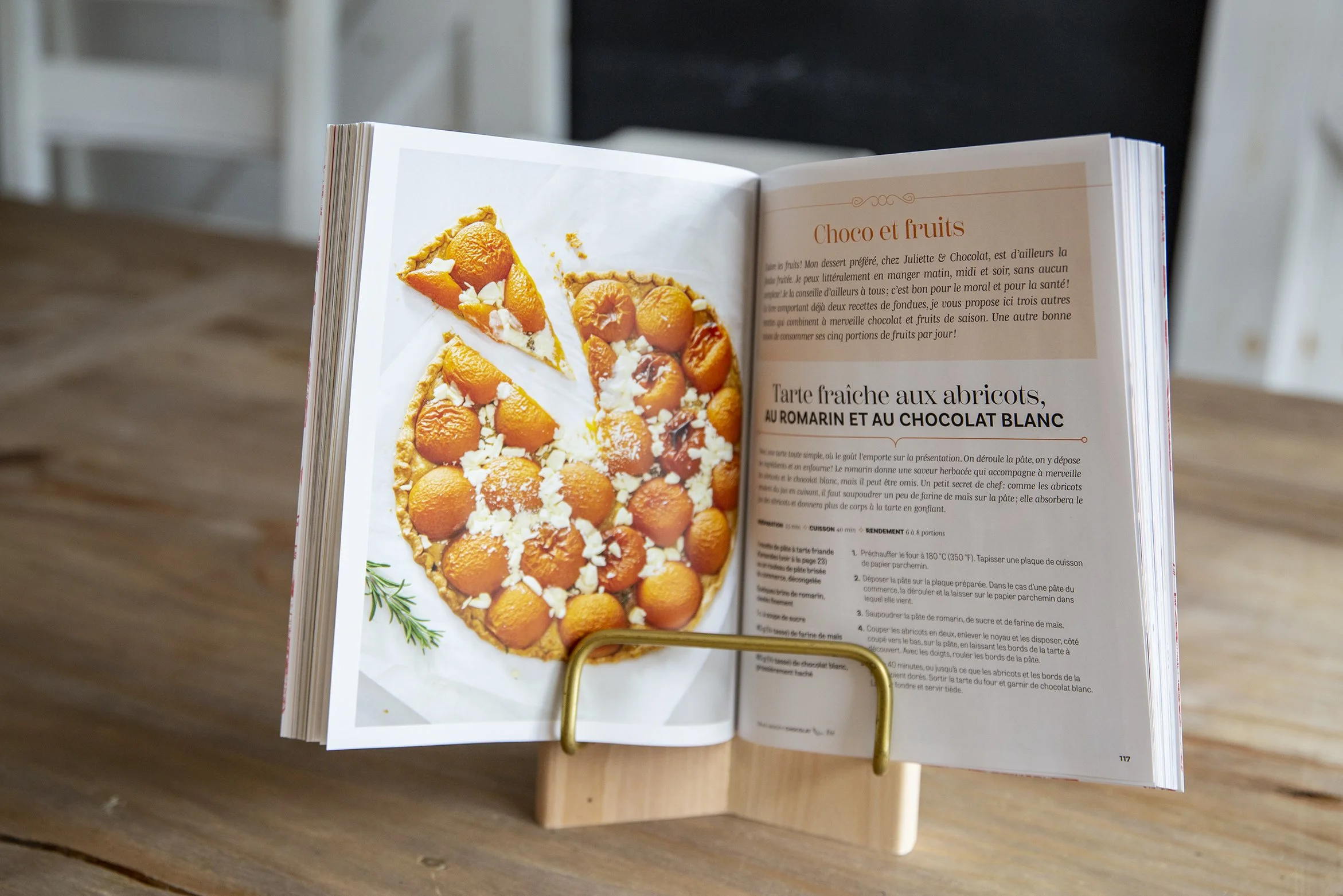 Open cookbook on a kitchen counter showing an apricot and white chocolate tart